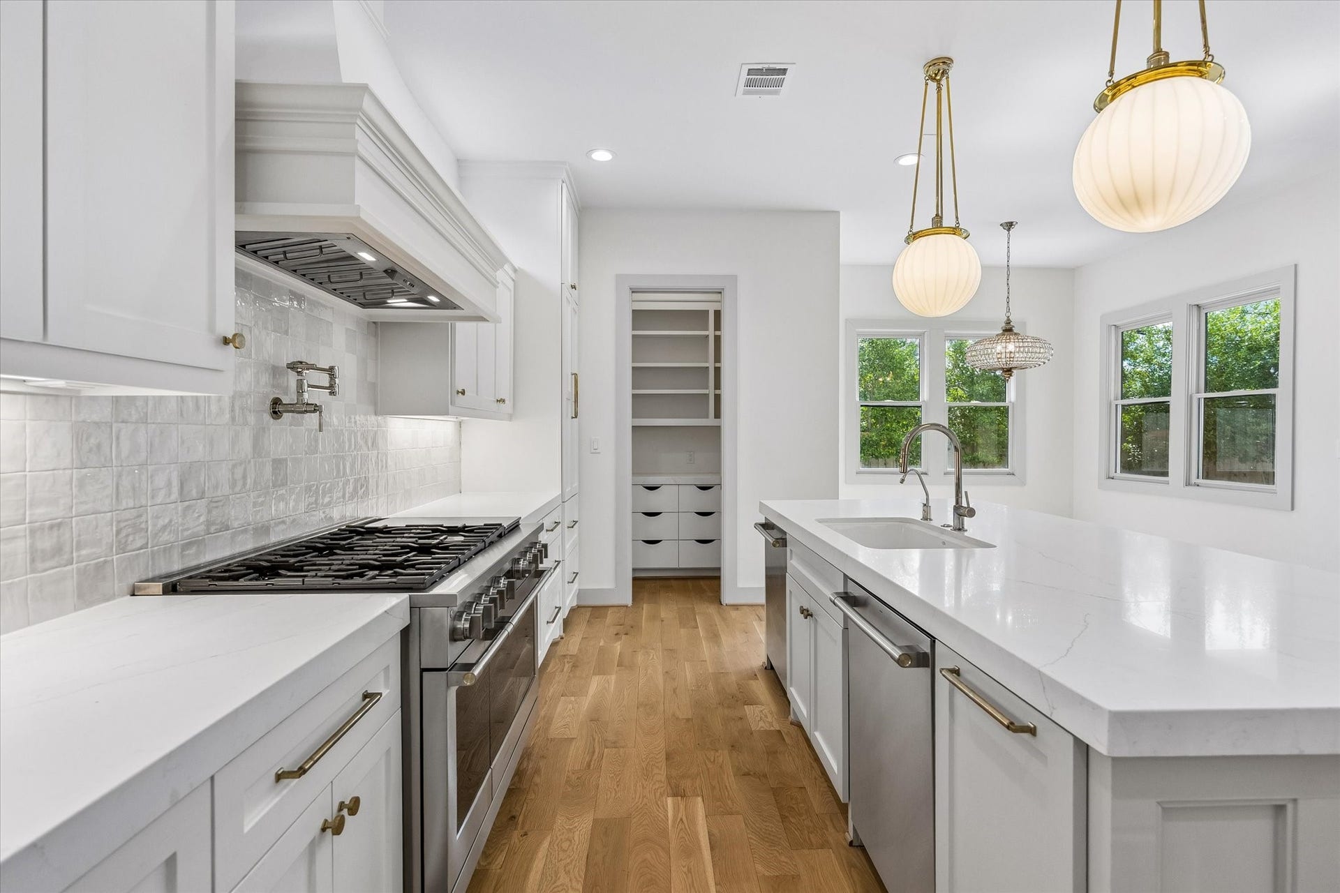 704 Teetshorn Street, Houston, TX 77009 Stainless gas range, custom vent hood, pot filler and textured tile backsplash create a polished focal point in the kitchen