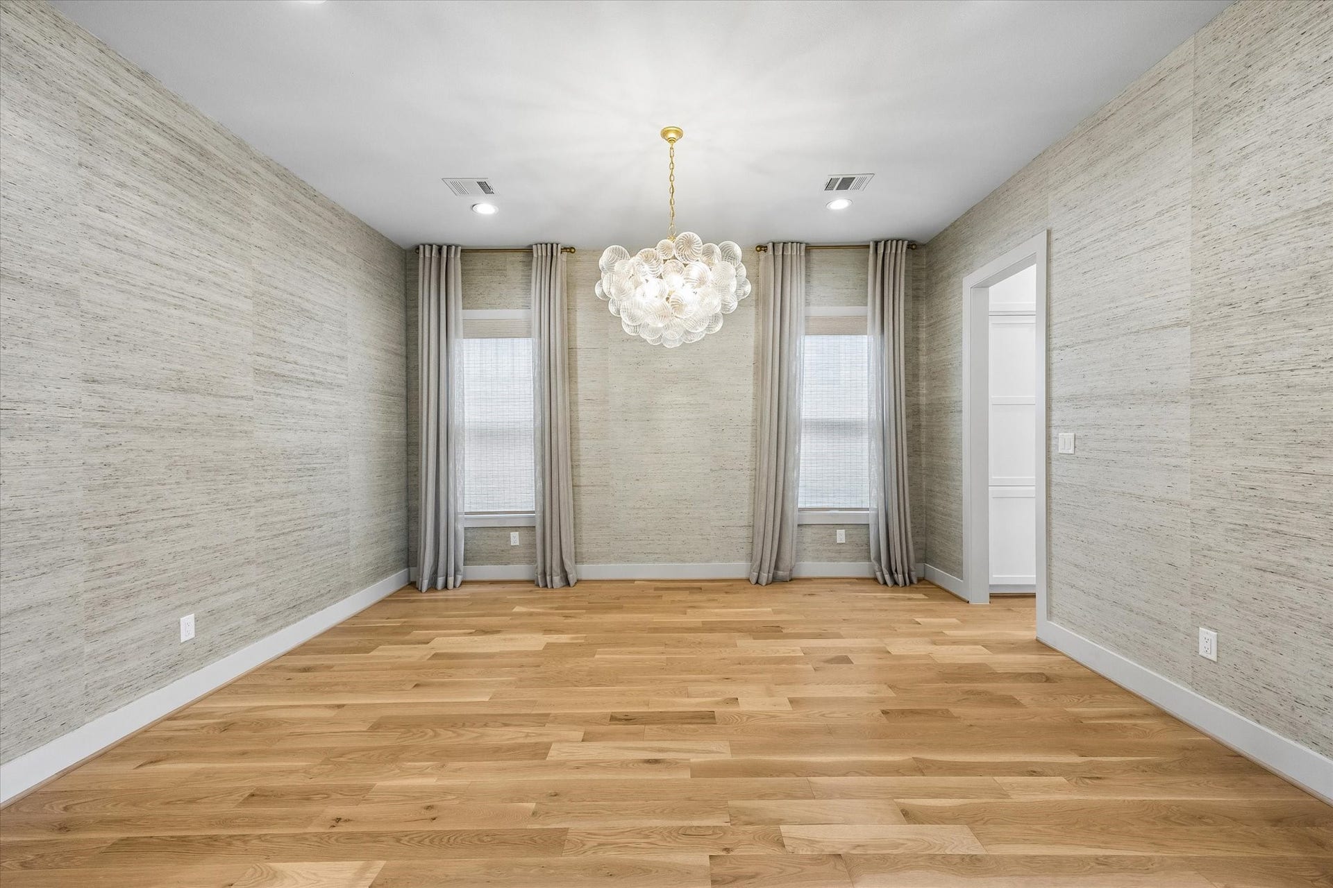 704 Teetshorn Street, Houston, TX 77009 Formal dining room with hardwood floors, textured wallcovering and a statement chandelier.