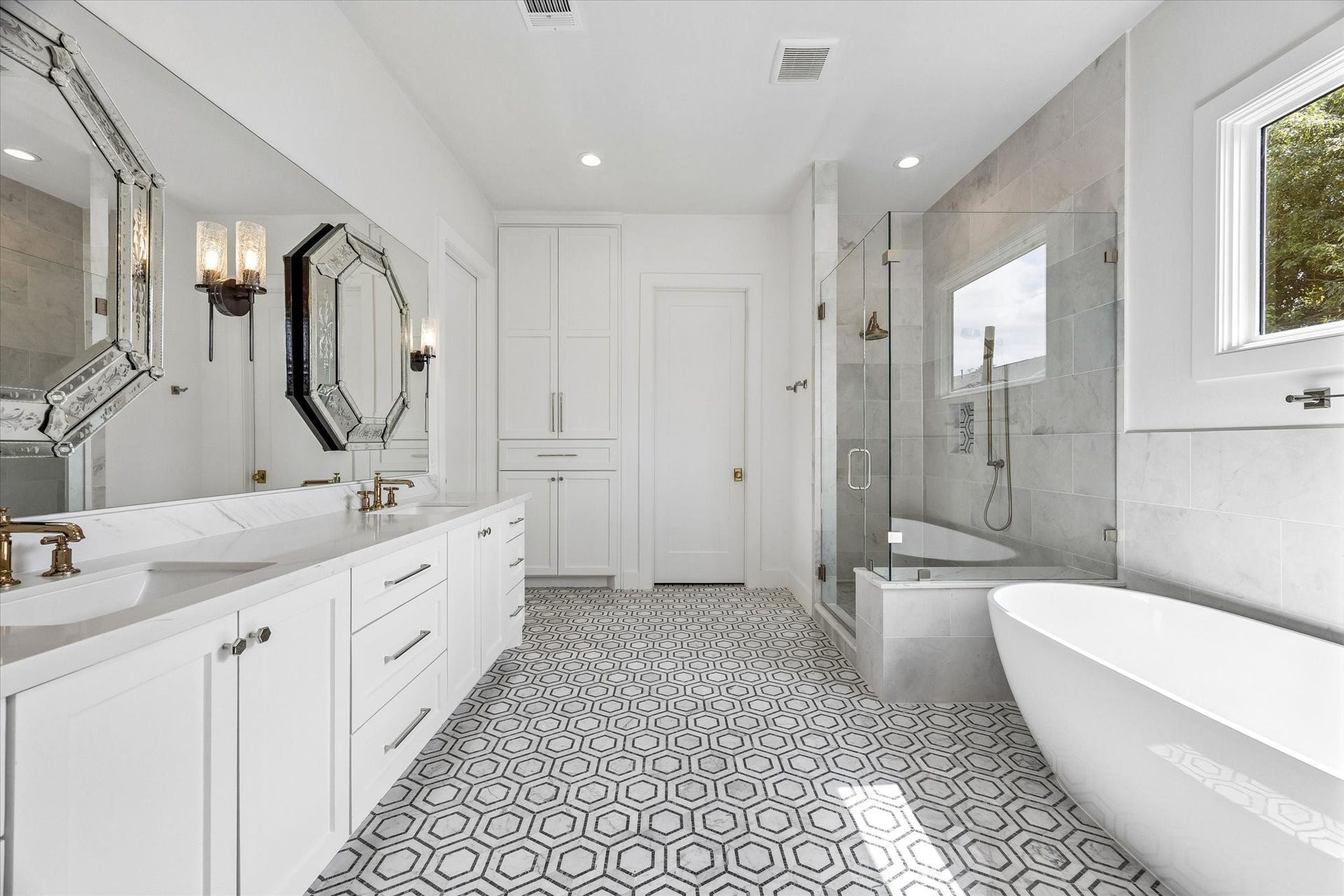 704 Teetshorn Street, Houston, TX 77009 Spa-inspired primary bath with a long dual vanity, soaking tub, glass-enclosed shower and graphic patterned flooring.