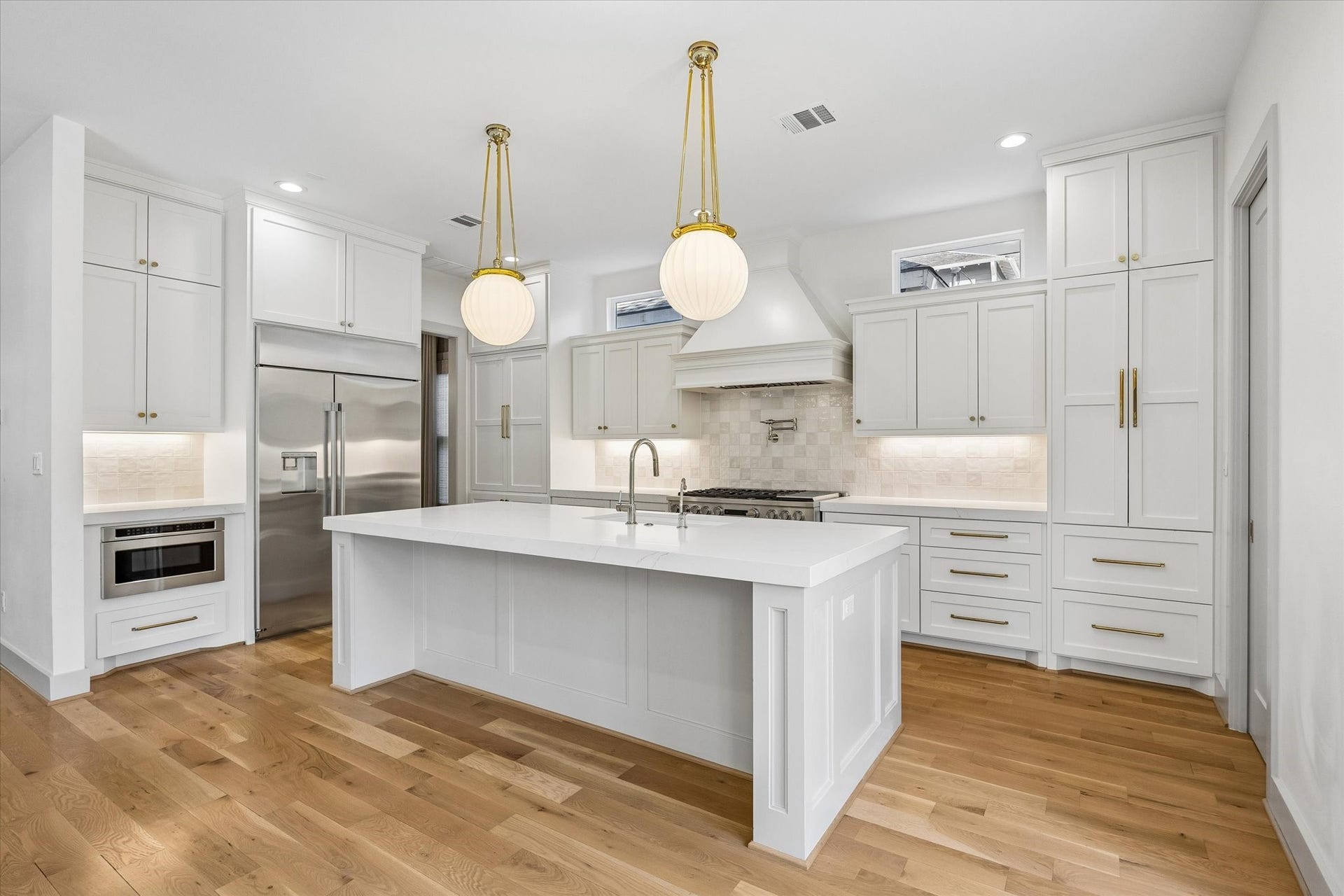 704 Teetshorn Street, Houston, TX 77009 The living area opens seamlessly to the kitchen, with hardwood floors and oversized glass doors overlooking the backyard.