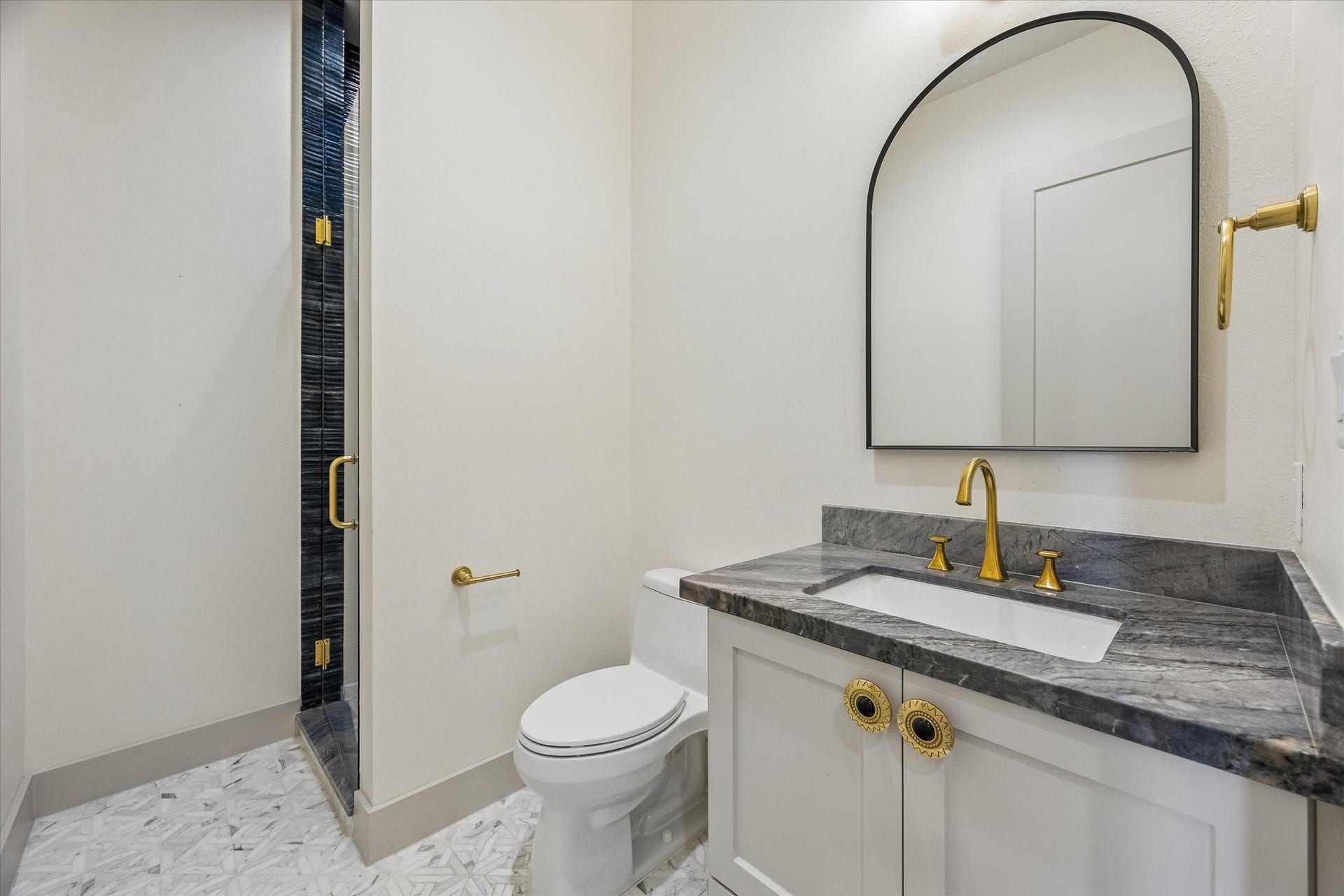 704 Teetshorn Street, Houston, TX 77009 Convenient first-floor full bath located near the study, finished with a marble-topped vanity and brass accents.