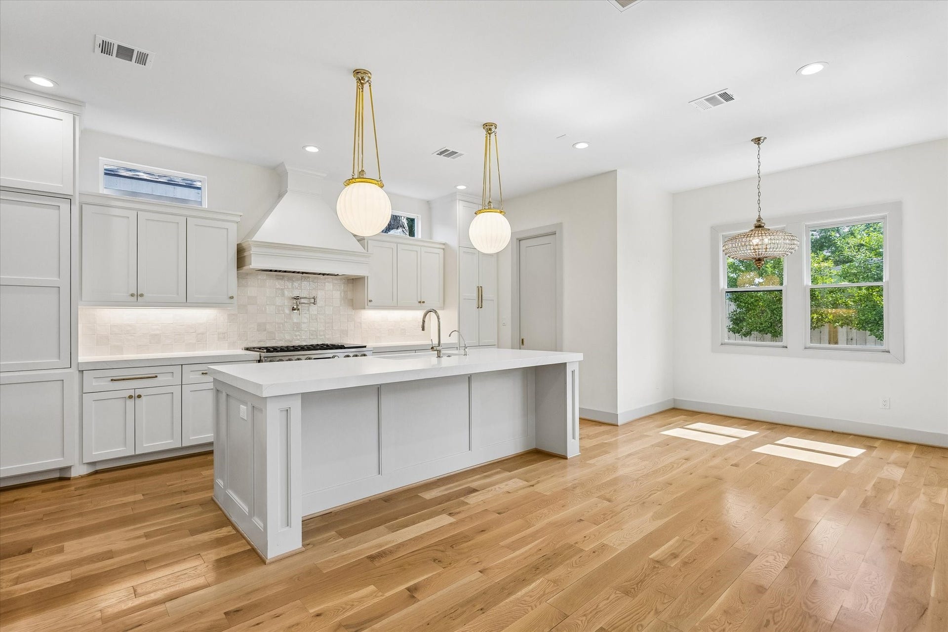 704 Teetshorn Street, Houston, TX 77009 Generous cabinetry and a substantial island provide ample prep and storage space, complemented by pendant lighting and warm brass hardware.