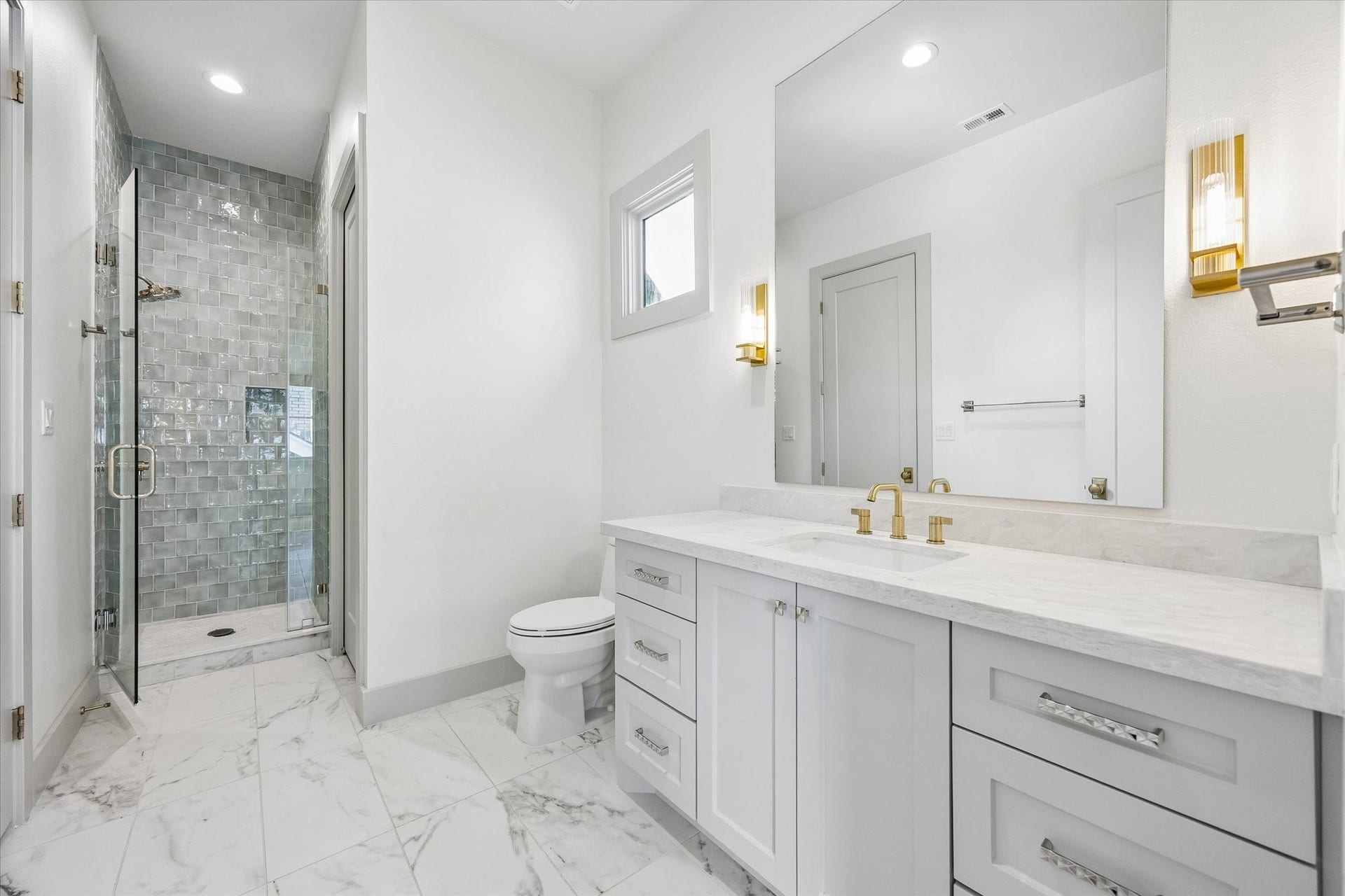 704 Teetshorn Street, Houston, TX 77009 Private en suite bath with marble-look flooring, a generous vanity and glass-enclosed shower.