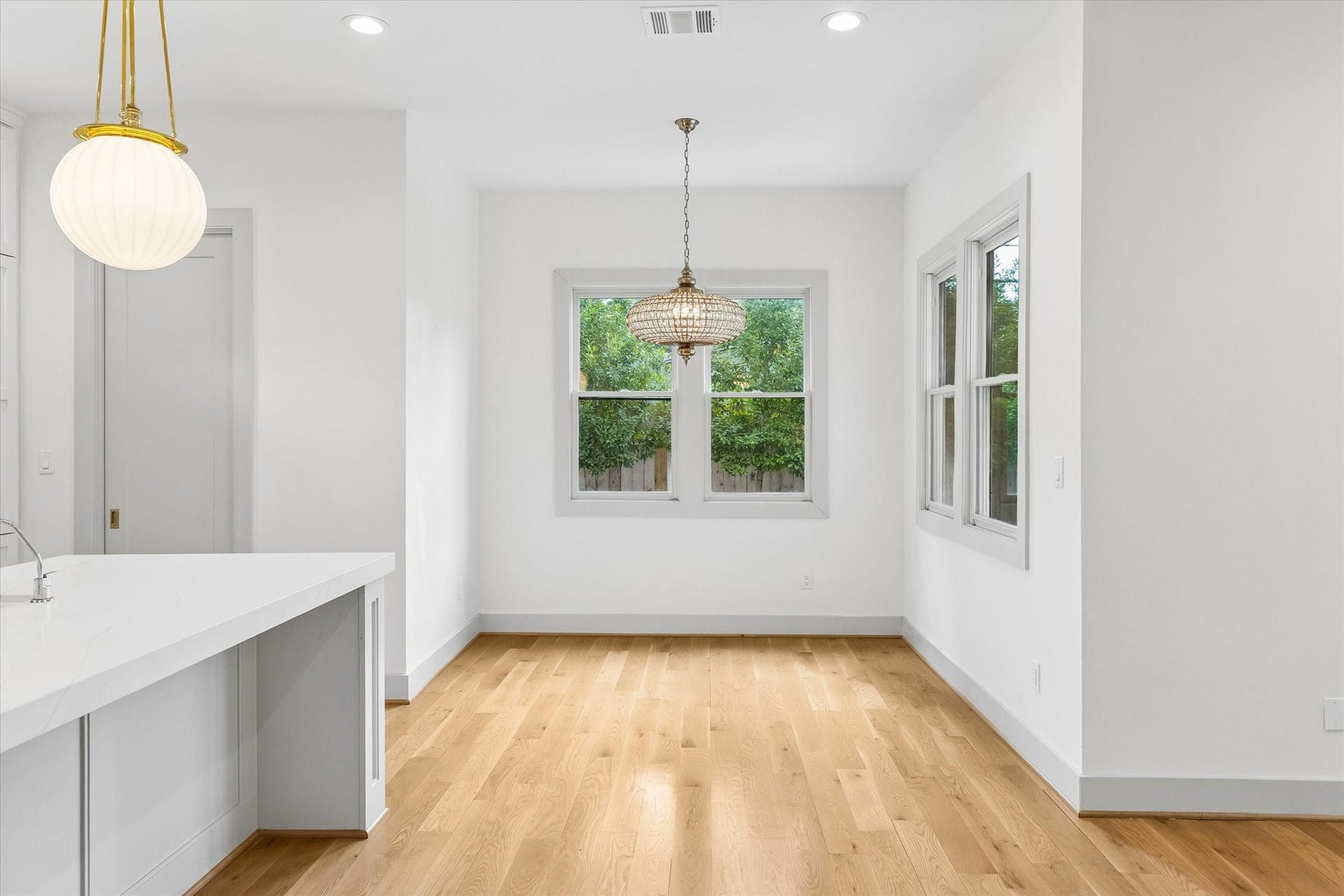 704 Teetshorn Street, Houston, TX 77009 Bright breakfast area framed by multiple windows and a statement chandelier, with easy access to the kitchen.