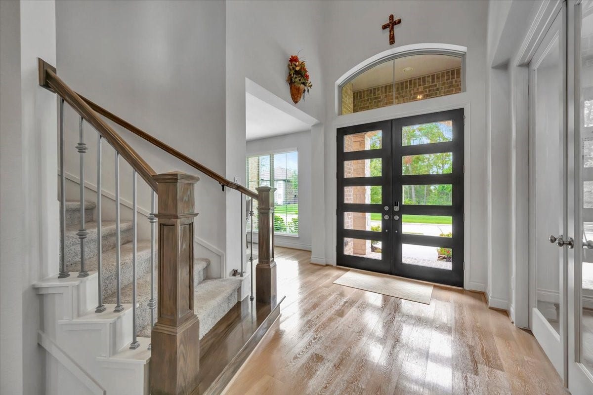 12218 Hickory Arroyo Drive, Humble, TX 77346 Inviting entryway features elegant hardwood floors, a modern double door with glass panels, and a stylish staircase, offering a warm welcome with abundant natural light.