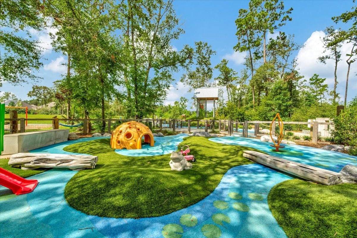 12218 Hickory Arroyo Drive, Humble, TX 77346 Charming outdoor play area nestled in lush greenery, featuring colorful slides, a climbing dome, and whimsical pathways perfect for children's adventures.