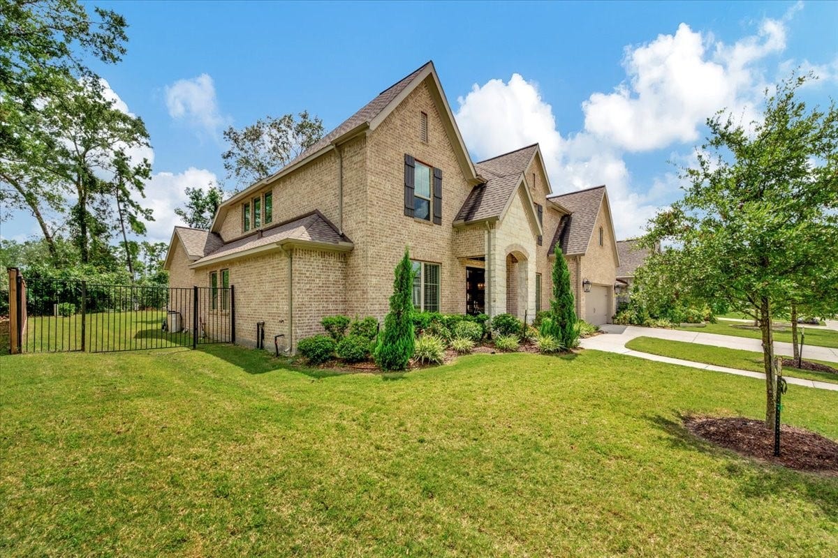 12218 Hickory Arroyo Drive, Humble, TX 77346 Stunning brick home with a charming gabled roof, lush landscaping, and a spacious, inviting front yard.