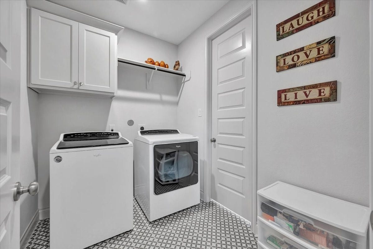 12218 Hickory Arroyo Drive, Humble, TX 77346 Modern laundry room featuring sleek appliances, ample cabinet storage, and stylish tiled flooring, perfect for efficient and organized living.