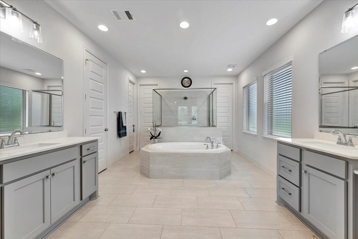 12218 Hickory Arroyo Drive, Humble, TX 77346 Experience a spa-like retreat in this master bathroom, featuring a unique design with a luxurious tub and a spacious walk-in shower.