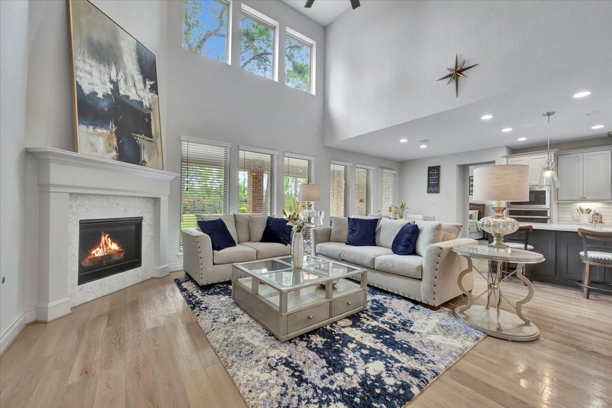 12218 Hickory Arroyo Drive, Humble, TX 77346 Experience the grandeur of this living room with its soaring two-story ceilings, abundant natural light, and an inviting fireplace, creating the perfect blend of elegance and comfort.