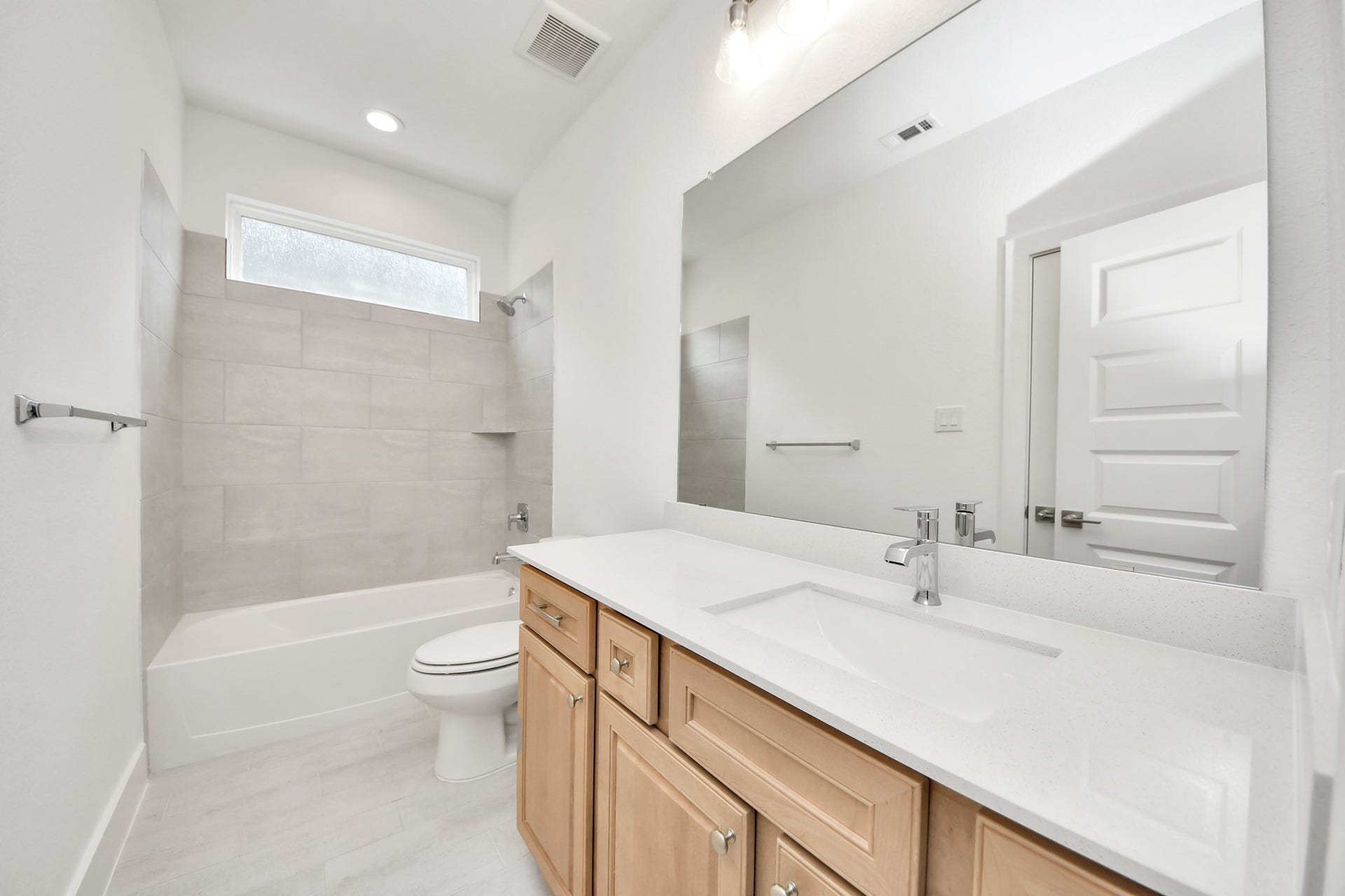 3221 Skerne Spring Drive, Spring, TX 77373 Secondary bath features tile flooring, bath/shower combo with tile surround, light stained wood cabinets, beautiful light countertop. Sample photo of completed home with similar floor plan. Actual colors and selections may vary.