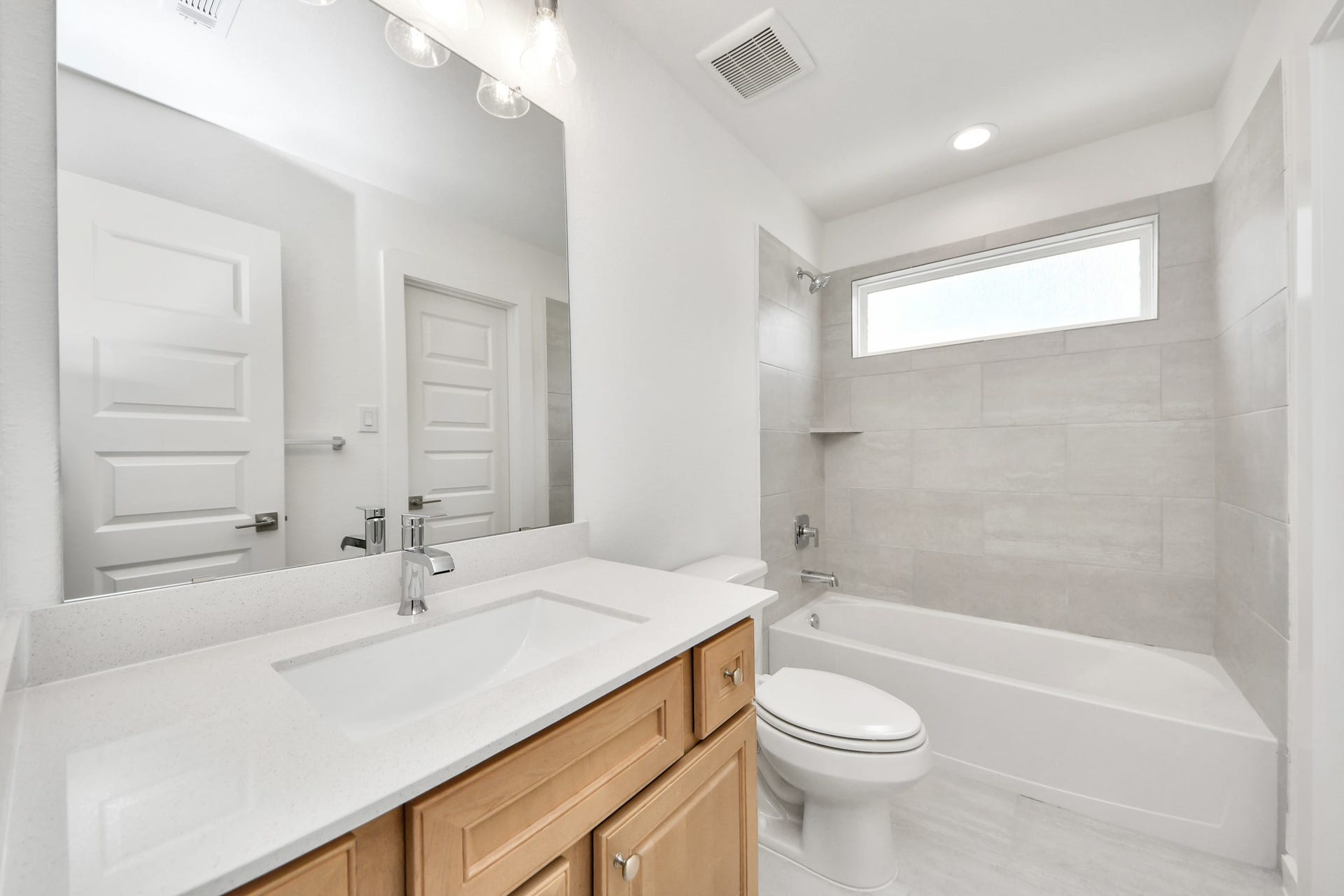 3221 Skerne Spring Drive, Spring, TX 77373 Secondary bath features tile flooring, bath/shower combo with tile surround, light stained wood cabinets, beautiful light countertop. Sample photo of completed home with similar floor plan. Actual colors and selections may vary.