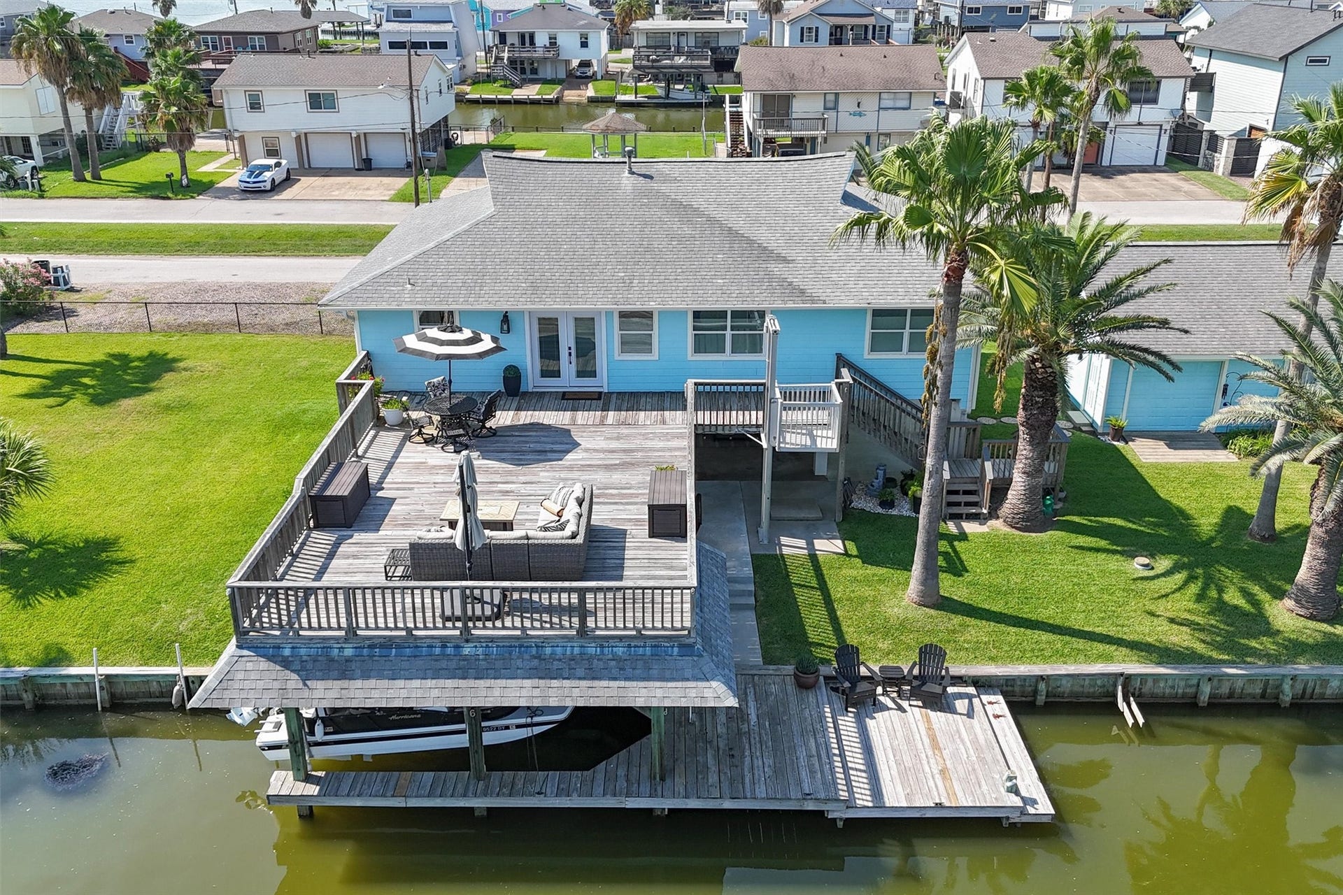 276 Barracuda Street, Bayou Vista, TX 77563 A stunning aerial view highlights this spacious home, featuring a large upper party deck, a convenient garage, and an adjacent empty lot offering endless possibilities. Perfect for entertaining and expansion in a prime location.