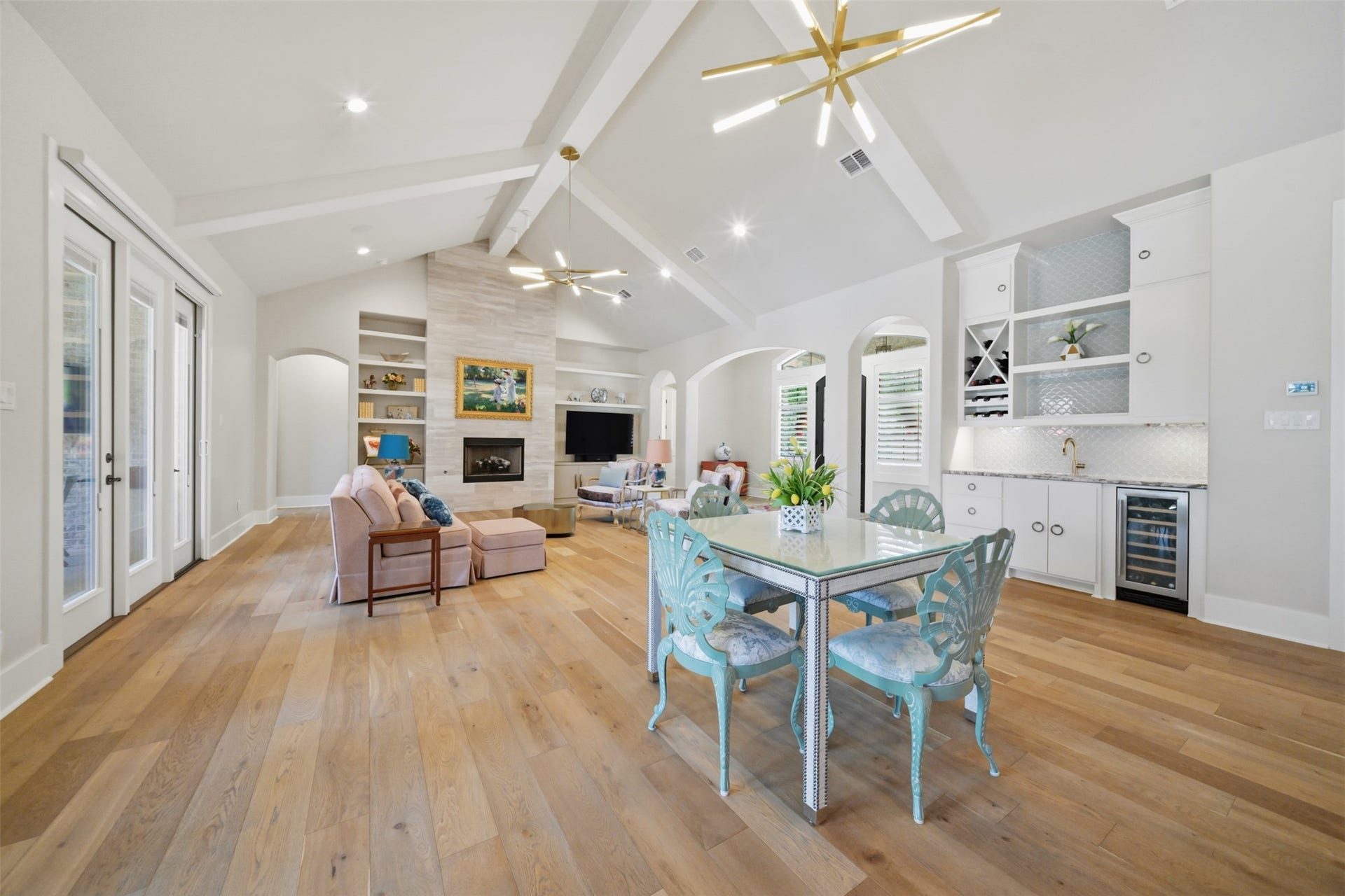5117 Inverness Drive, Bryan, TX 77802 Oversized open dining area with room for a large dining table, conveniently positioned beside the wet bar, with custom built-ins, beverage refrigerator, wide-plank wood flooring and soaring beamed ceiling.