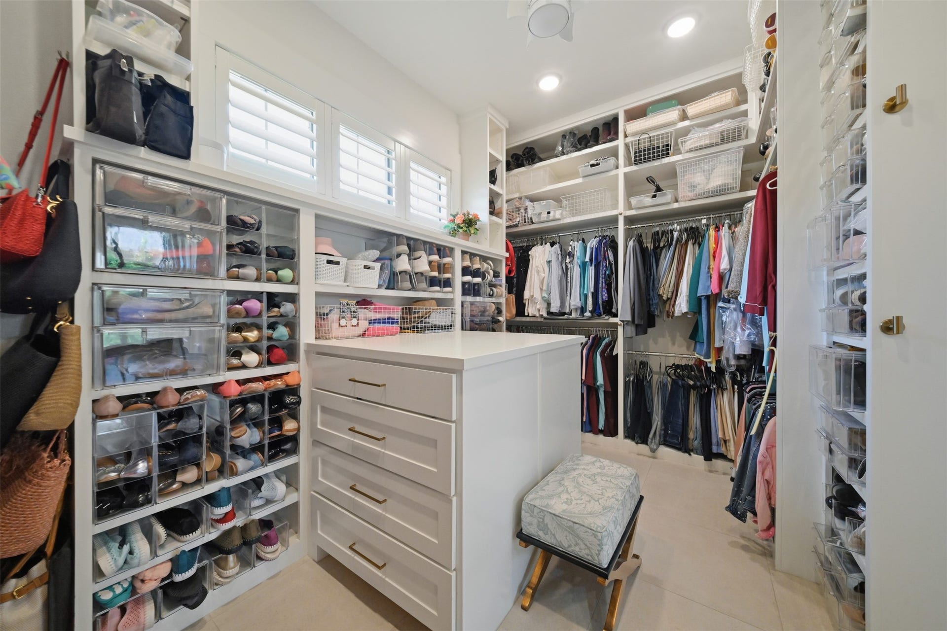 5117 Inverness Drive, Bryan, TX 77802 Roomy primary closet with custom built-ins, abundant hanging and shoe storage, a center storage island, and direct access to both the primary bathroom and laundry room.