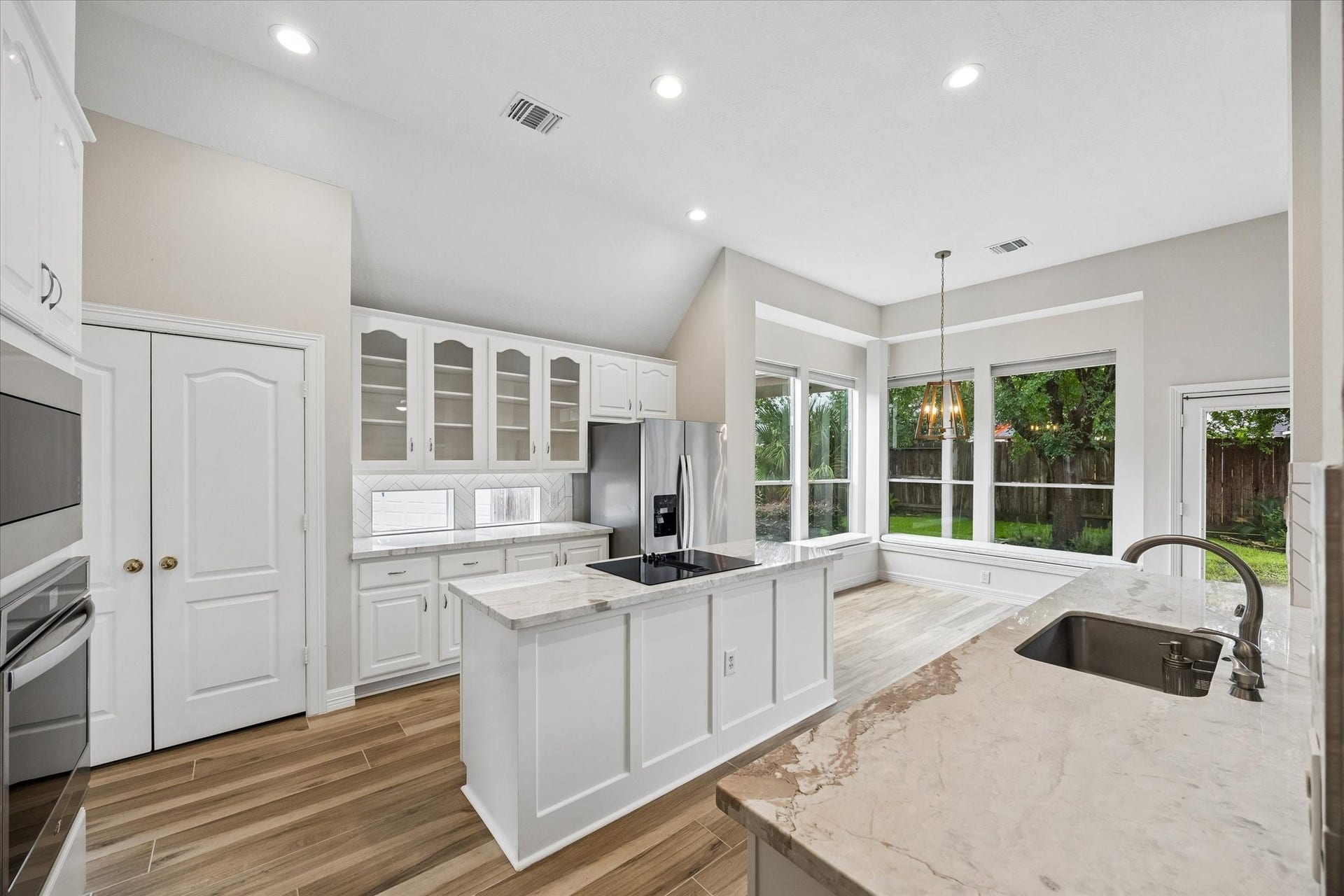 5306 Summerland Ridge Court, Houston, TX 77041 The kitchen sports a center island with storage below, glass-front display cabinetry, and quartz countertops.