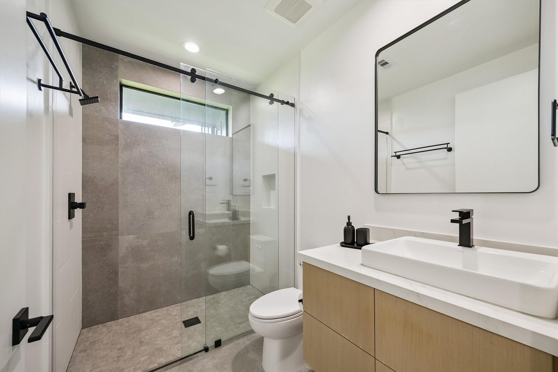 5210 Manor Drive, Sugar Land, TX 77479 Beautifully coordinated finishes, a glass-enclosed shower, and sleek black fixtures give this guest bathroom a fresh, sophisticated aesthetic.