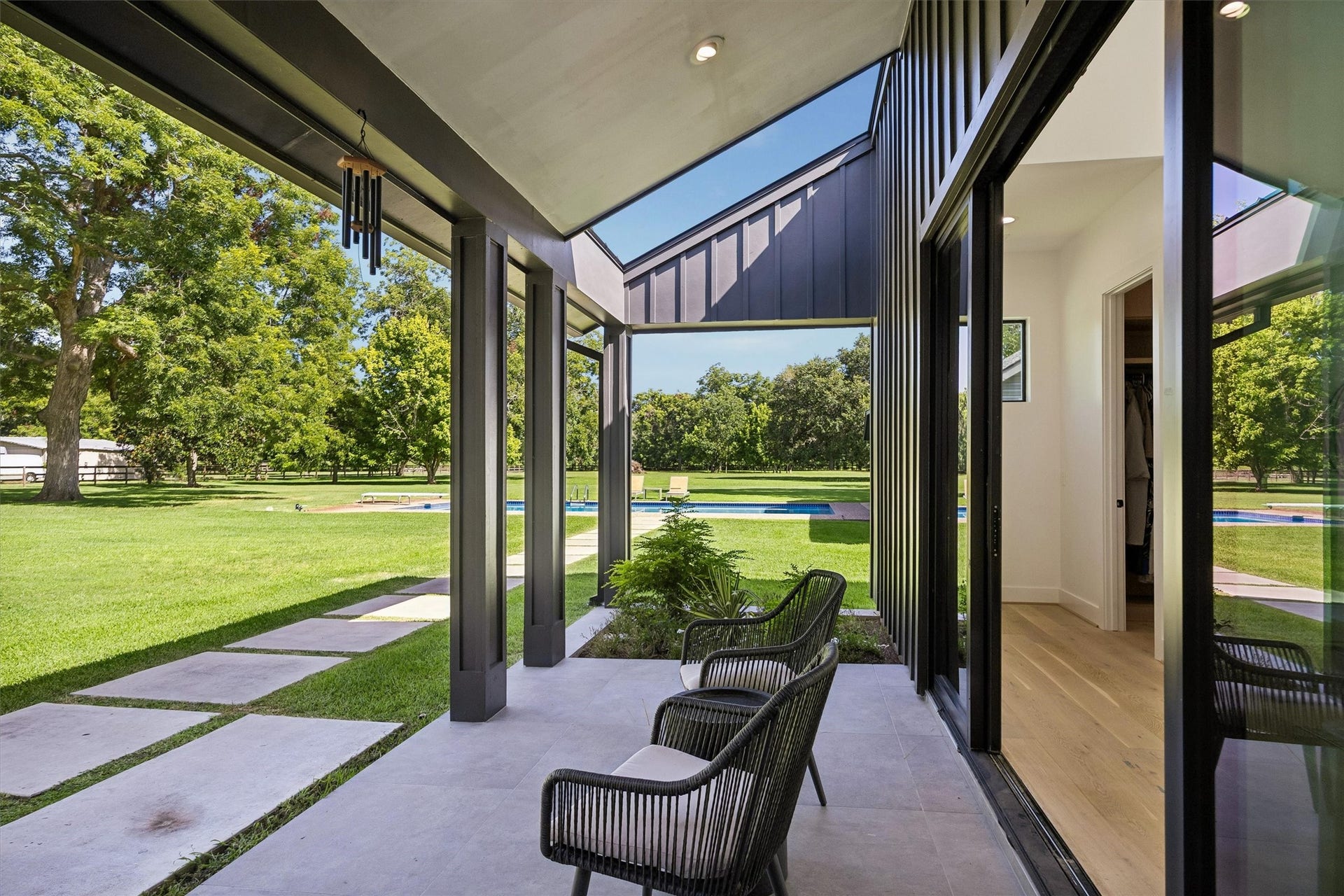 5210 Manor Drive, Sugar Land, TX 77479 Floor-to-ceiling glass and a sheltered sitting area invite the surrounding landscape into view, creating a peaceful transition between the residence and its beautifully maintained outdoor spaces.
