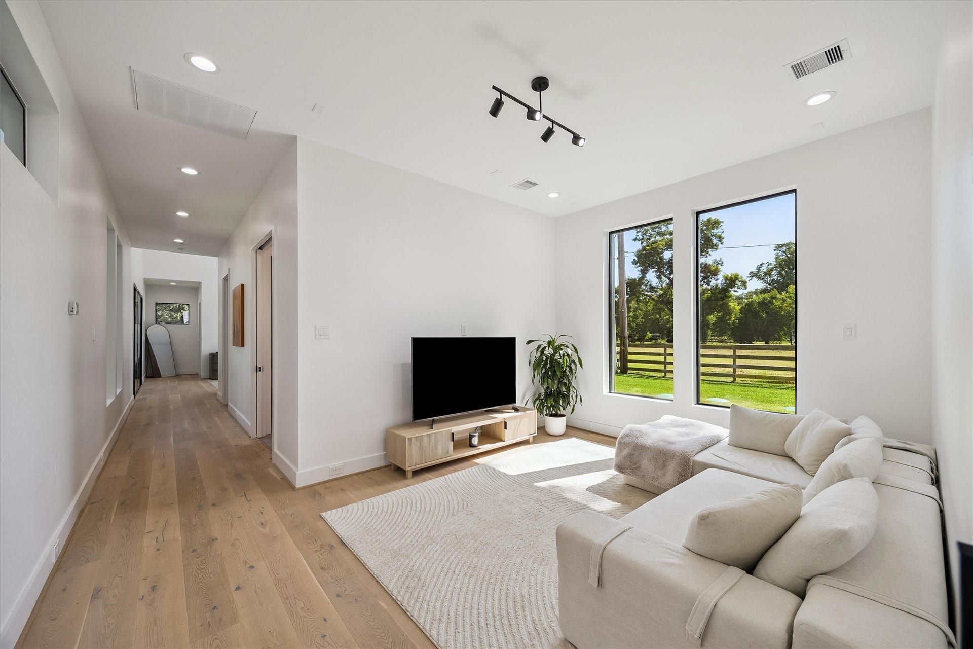5210 Manor Drive, Sugar Land, TX 77479 A serene sitting area within the primary wing offers a peaceful escape, where expansive windows invite natural light and showcase the beautifully landscaped grounds.
