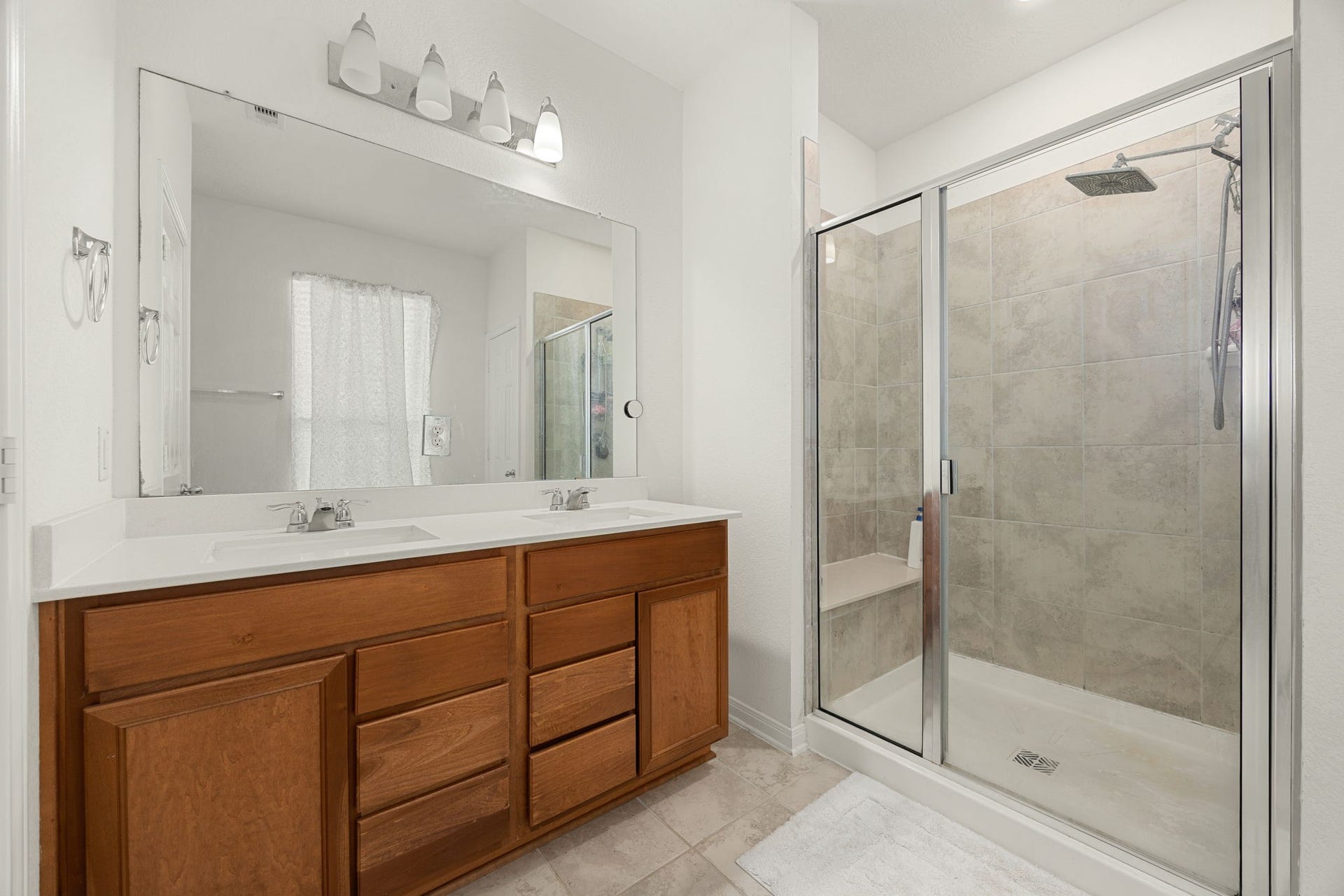 2023 Katalonia Lane, Fresno, TX 77459 Pamper yourself in the well-appointed primary bathroom, highlighting excellent storage capacity and clean finishes. The oversized step-in shower boasts a premium rain-style showerhead and dedicated seating, beautifully complementing the long wood-toned vanity with two sinks, durable tile flooring, and bright, high-ceiling layout.