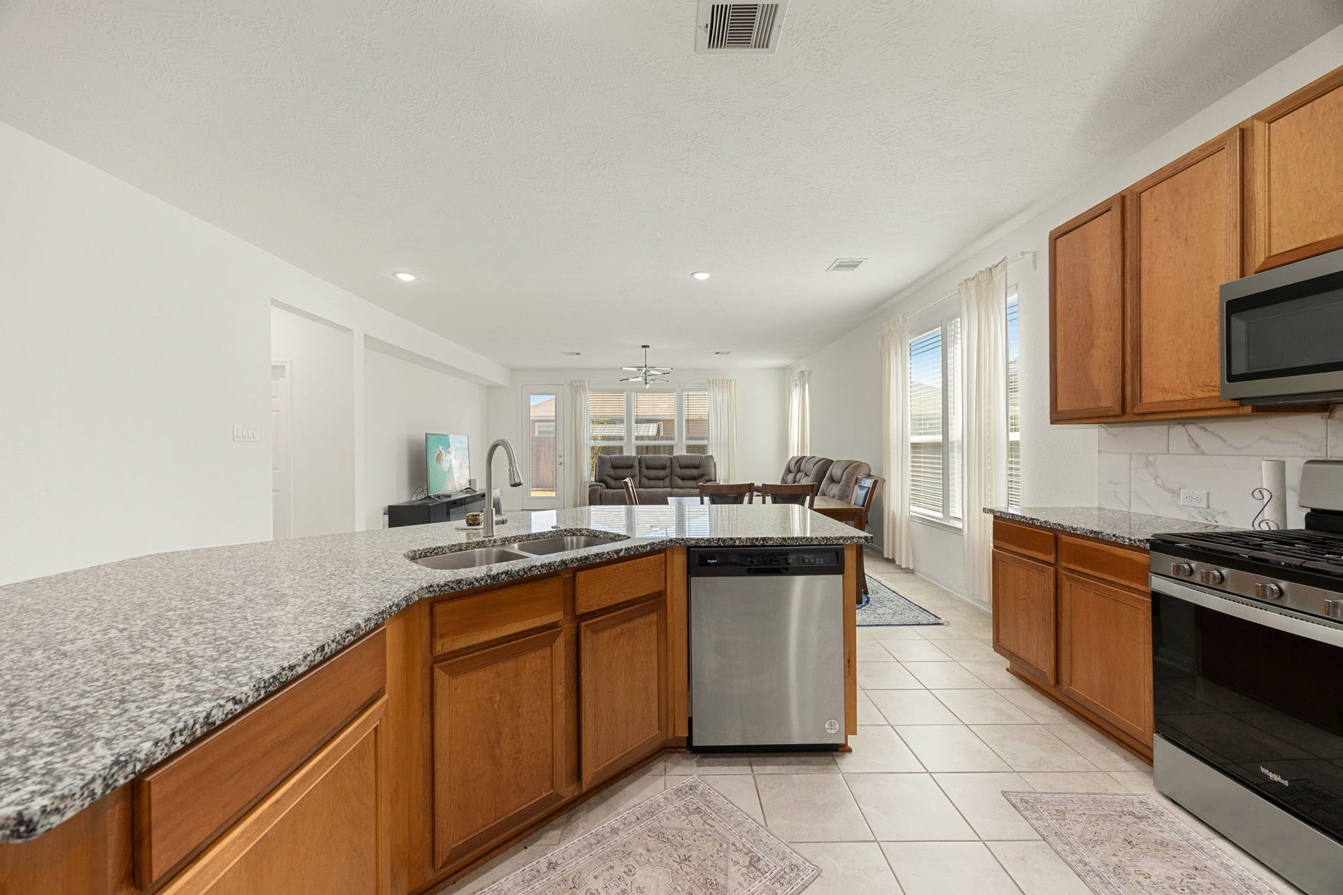 2023 Katalonia Lane, Fresno, TX 77459 The oversized, uniquely angled kitchen island serves as the central focal point of the main living pavilion. This expansive workspace features durable granite countertops, an integrated double-bowl stainless steel sink with a goose-neck faucet, and a built-in stainless steel dishwasher, all while keeping the chef fully connected to the adjacent dining and living areas.