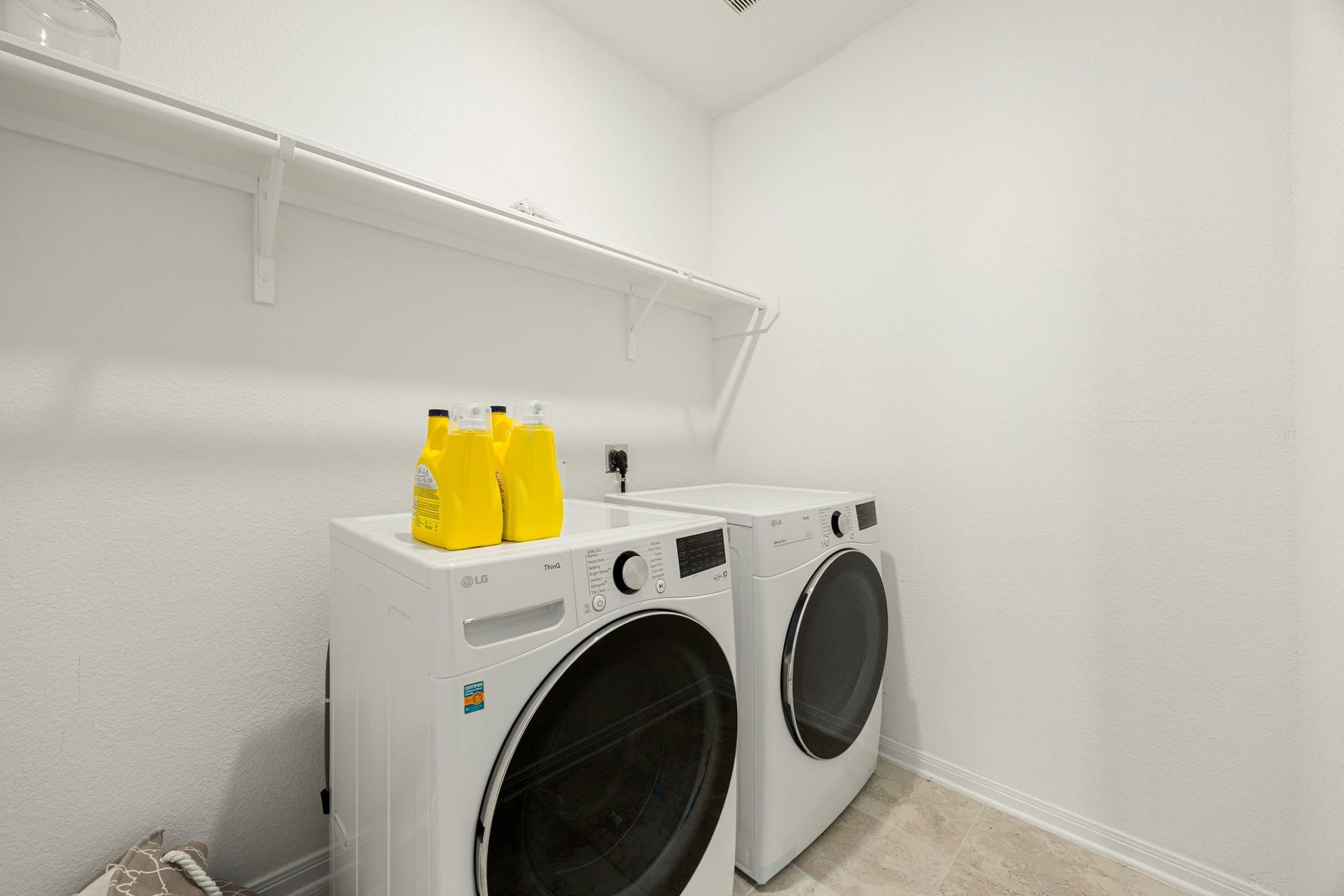 2023 Katalonia Lane, Fresno, TX 77459 A beautifully clean and bright laundry zone located conveniently within the home's layout. Modern recessed lighting illuminates the space, which boasts premium tile flooring and extensive overhead shelving, offering the perfect blend of practical workspace and organized storage.