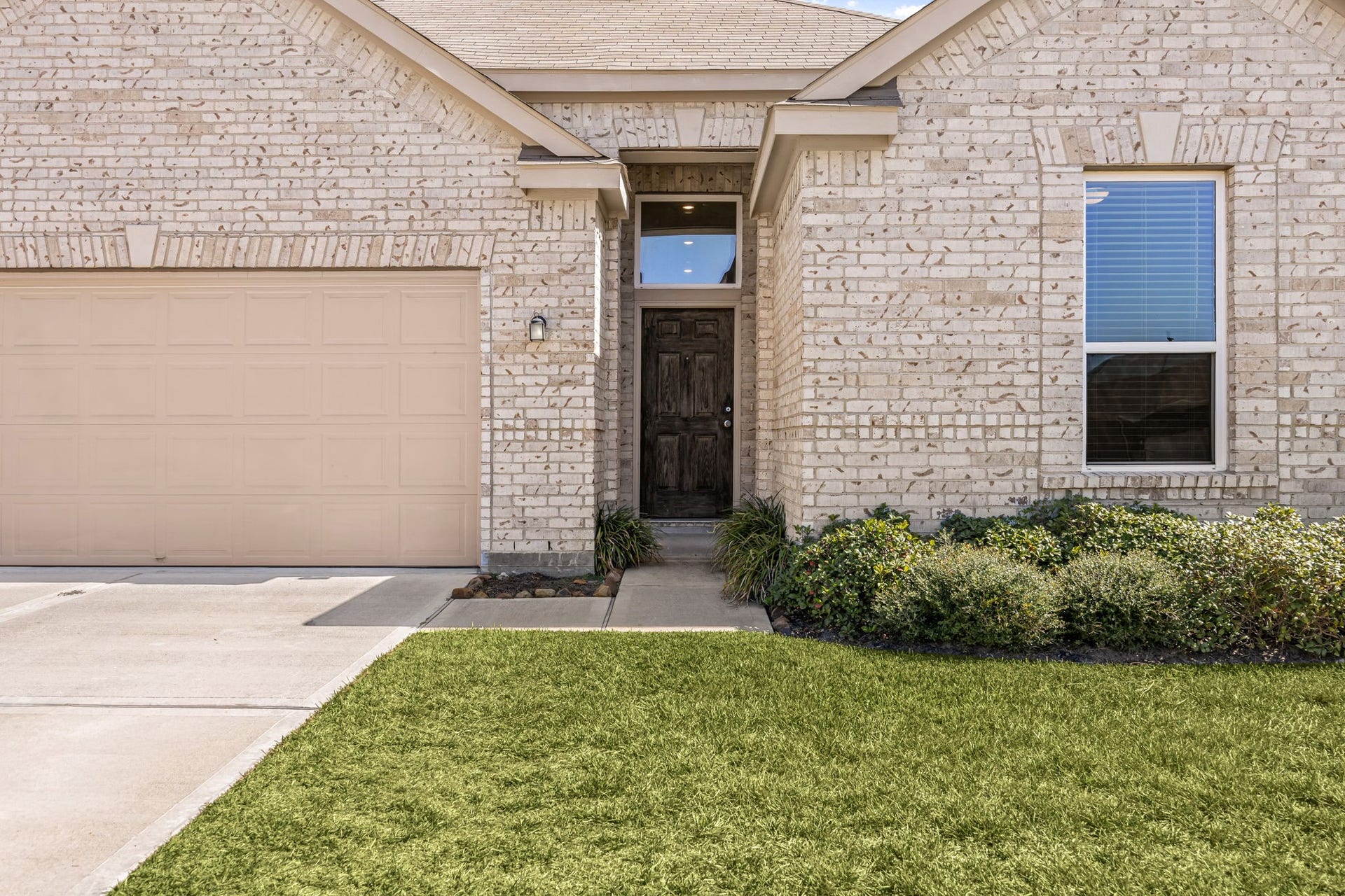 2023 Katalonia Lane, Fresno, TX 77459 This beautifully maintained brick home features a spacious two-car garage, a manicured front lawn, and an inviting covered entryway that opens up into a bright, welcoming interior.