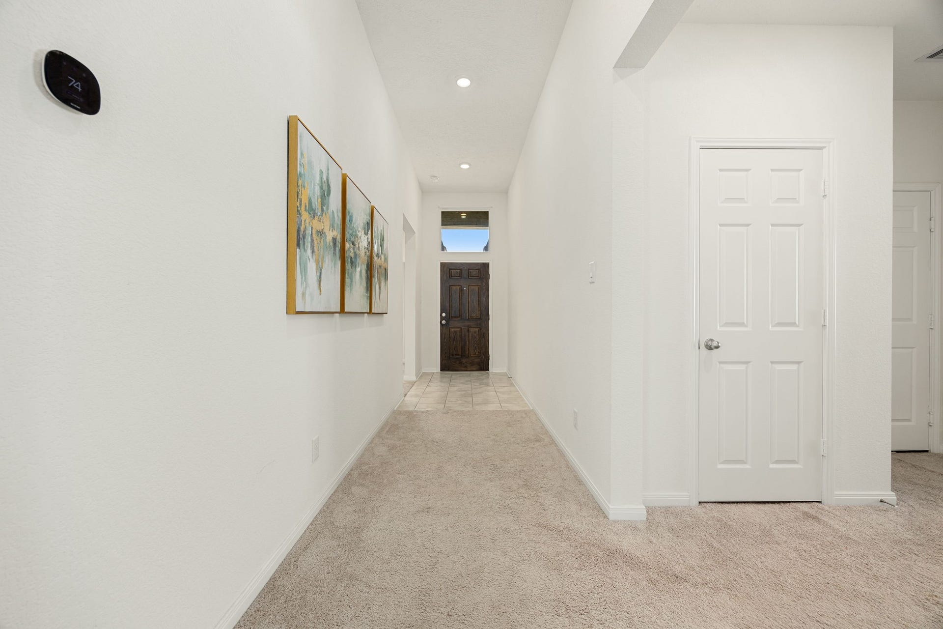 2023 Katalonia Lane, Fresno, TX 77459 A view looking back toward the front entry highlights the home's impressive high ceilings and spacious layout. This long, architectural hallway features neutral plush carpeting, modern recessed lighting, and crisp white walls that provide a bright and open atmosphere from the moment you step inside.