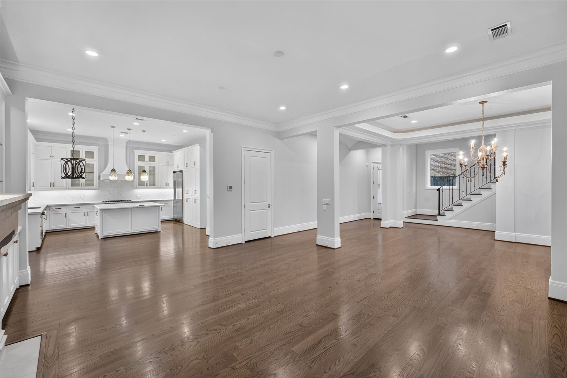 View from the NW corner of the living room: Open kitchen with breakfast area chandelier, the door to the right is the elevator ready closet used currently for storage.