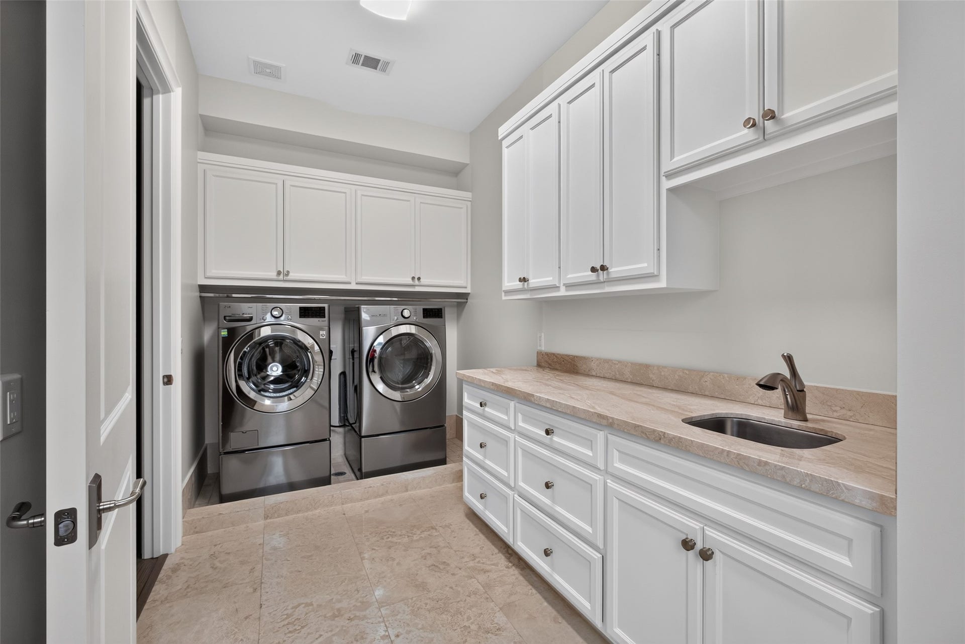Large laundry room with a ton of storage and a sink.  Washer and Dryer convey.