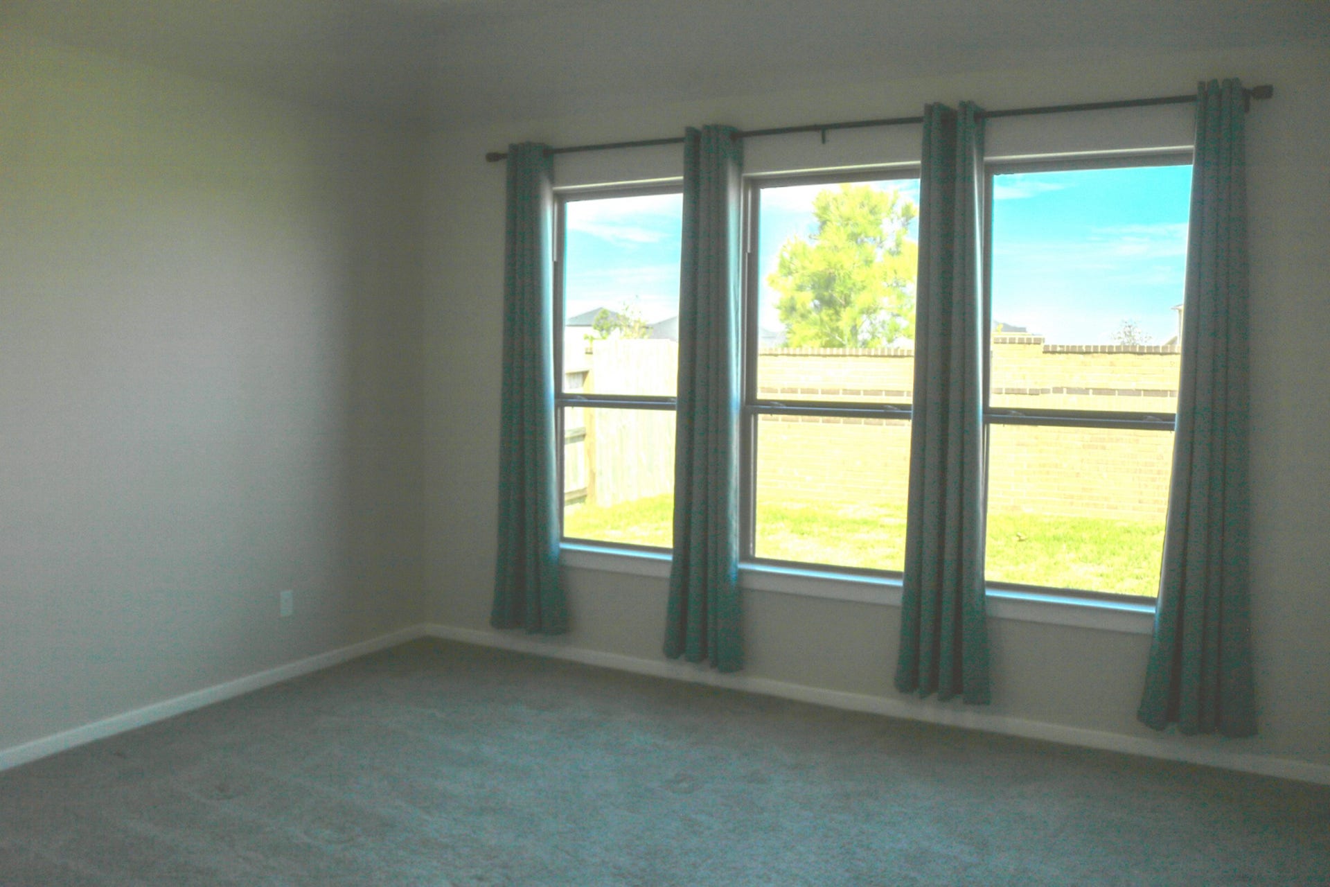 1007 Rosewood Trail, Beasley, TX 77417 Spacious primary bedroom downstairs featuring three large windows that welcome natural light, neutral tones, and soft carpeting. A comfortable retreat with plenty of room to relax and unwind.