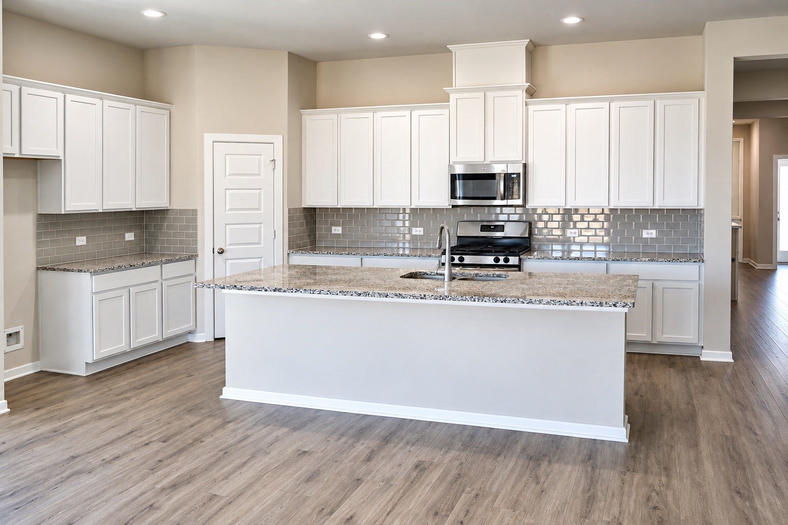 1007 Rosewood Trail, Beasley, TX 77417 Spacious kitchen featuring a large work island with seating, granite countertops, white cabinetry, stainless steel appliances, and a tile backsplash. Generous counter space and abundant storage make meal preparation and entertaining a breeze.