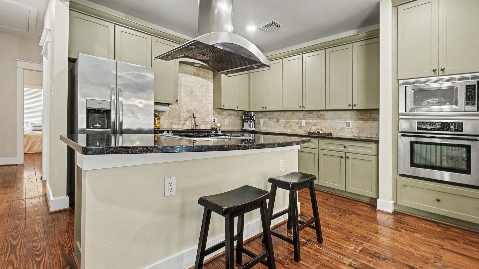 This island kitchen with gas cooktop has so much counter space and storage!  Stainless steel appliances, and tile backsplash.