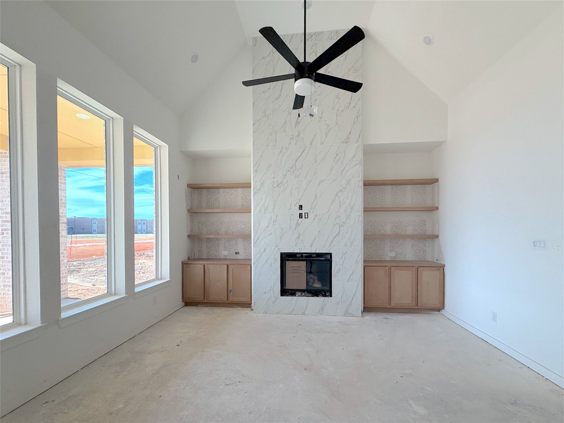 Bright family room featuring vaulted ceilings, a fireplace, and custom built-in shelving.