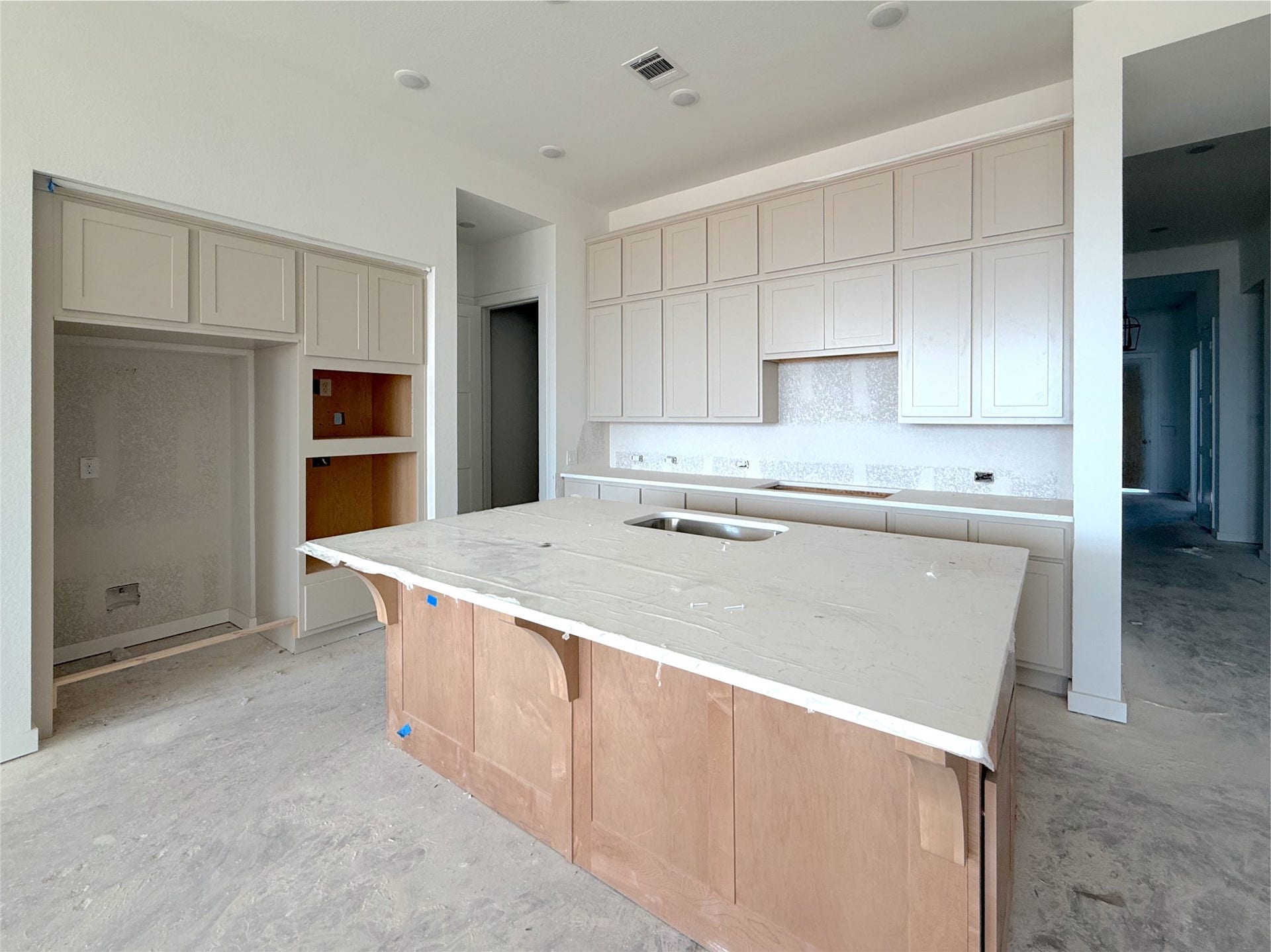 Designer kitchen featuring an oversized island with wrap around woodwork, stacked upper cabinets, and modern finishes