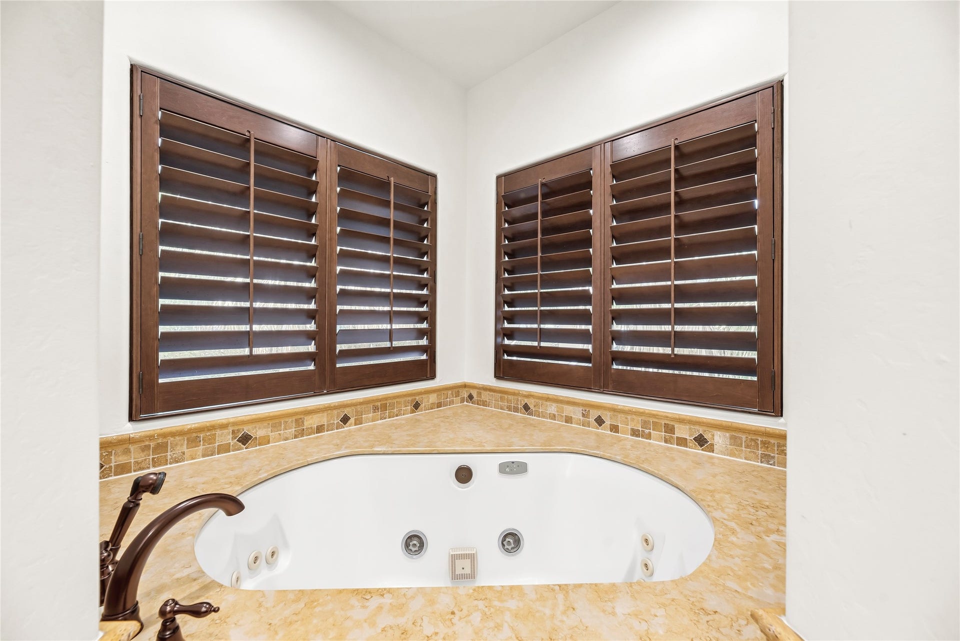 3803 Drake Street, Houston, TX 77005 A deep jetted tub is framed by elegant tile work and large windows, creating a peaceful corner to unwind after a long day.