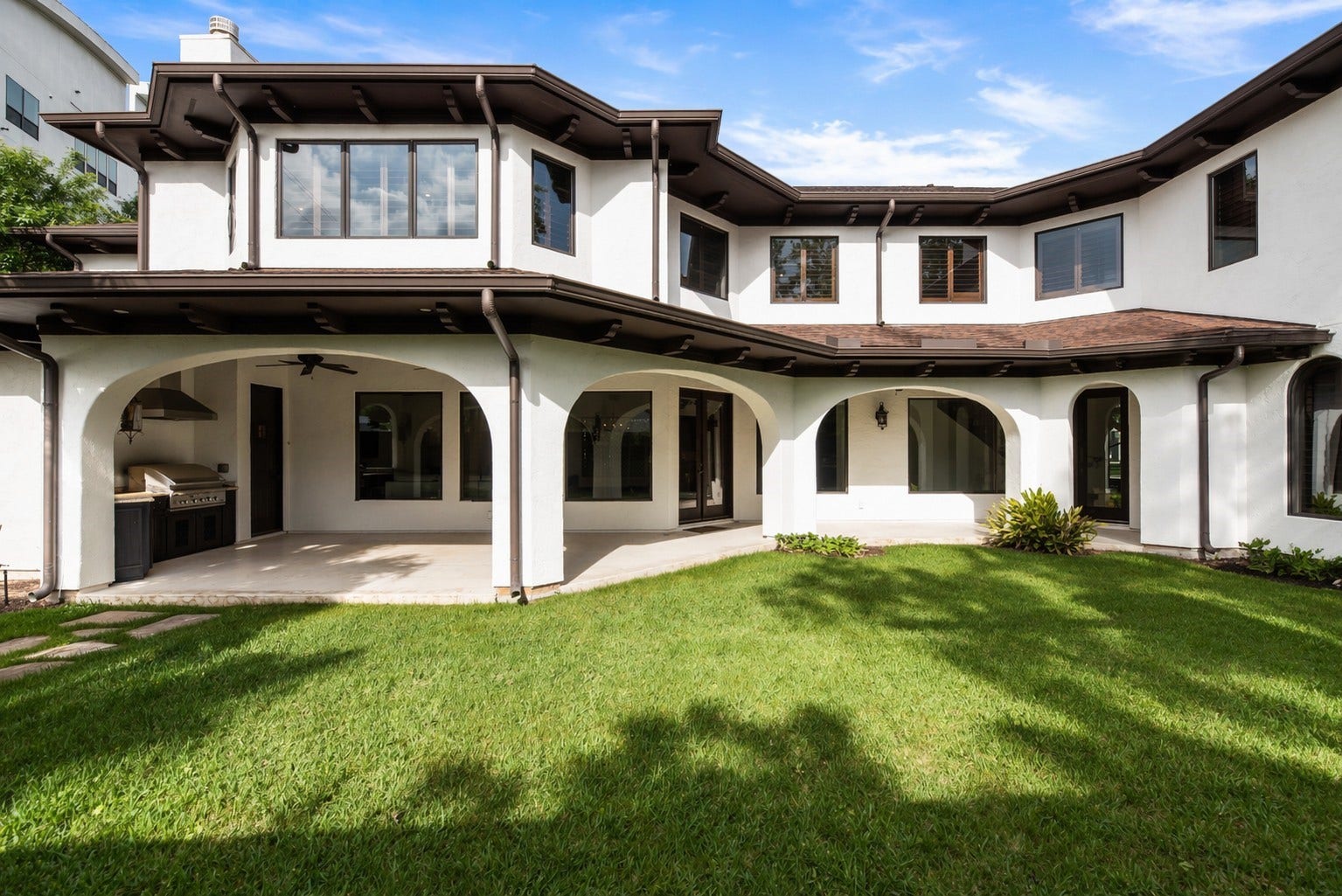 3803 Drake Street, Houston, TX 77005 The rear exterior features a sweeping arched loggia and a built-in summer kitchen, perfectly designed for seamless indoor-outdoor living.