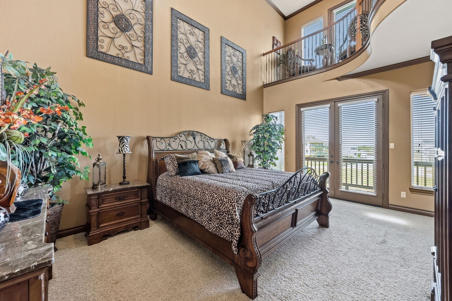 26 Half Moon, Hitchcock, TX 77563 Spacious primary bedroom with high ceilings and elegant decor, featuring a luxurious bed, large windows for natural light, and a charming loft area above.