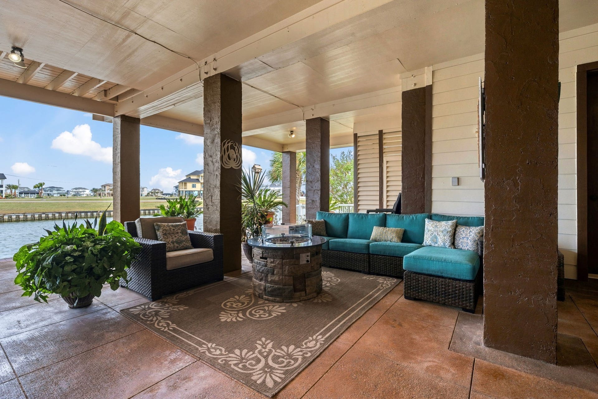 26 Half Moon, Hitchcock, TX 77563 Stylish covered patio with cozy seating, lush plants, and a tranquil water view, perfect for relaxing or entertaining.