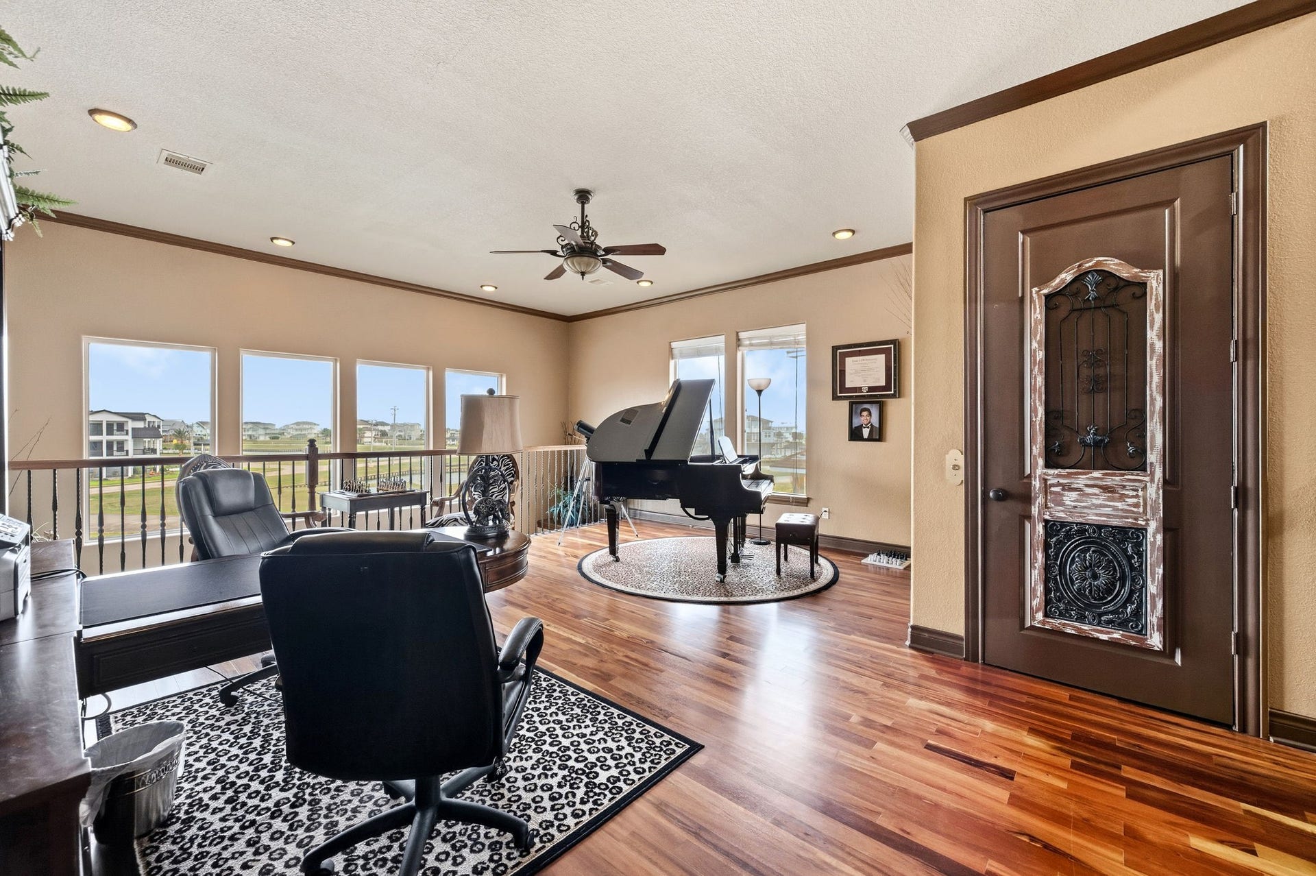 26 Half Moon, Hitchcock, TX 77563 Spacious and elegant home office featuring rich wood flooring, abundant natural light from large windows, and a sophisticated ambiance highlighted by a grand piano.