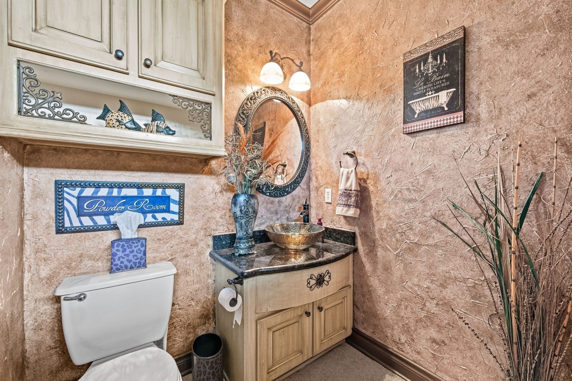 26 Half Moon, Hitchcock, TX 77563 Elegant hallway powder room with textured walls, a decorative mirror, and a stylish vessel sink set on a granite countertop, complemented by charming accents and cabinetry.