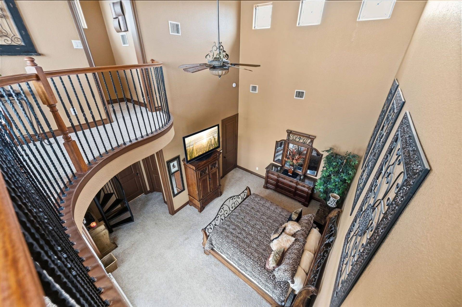 26 Half Moon, Hitchcock, TX 77563 Grand two-story bedroom with elegant wrought iron balcony, high ceilings, and abundant natural light.
