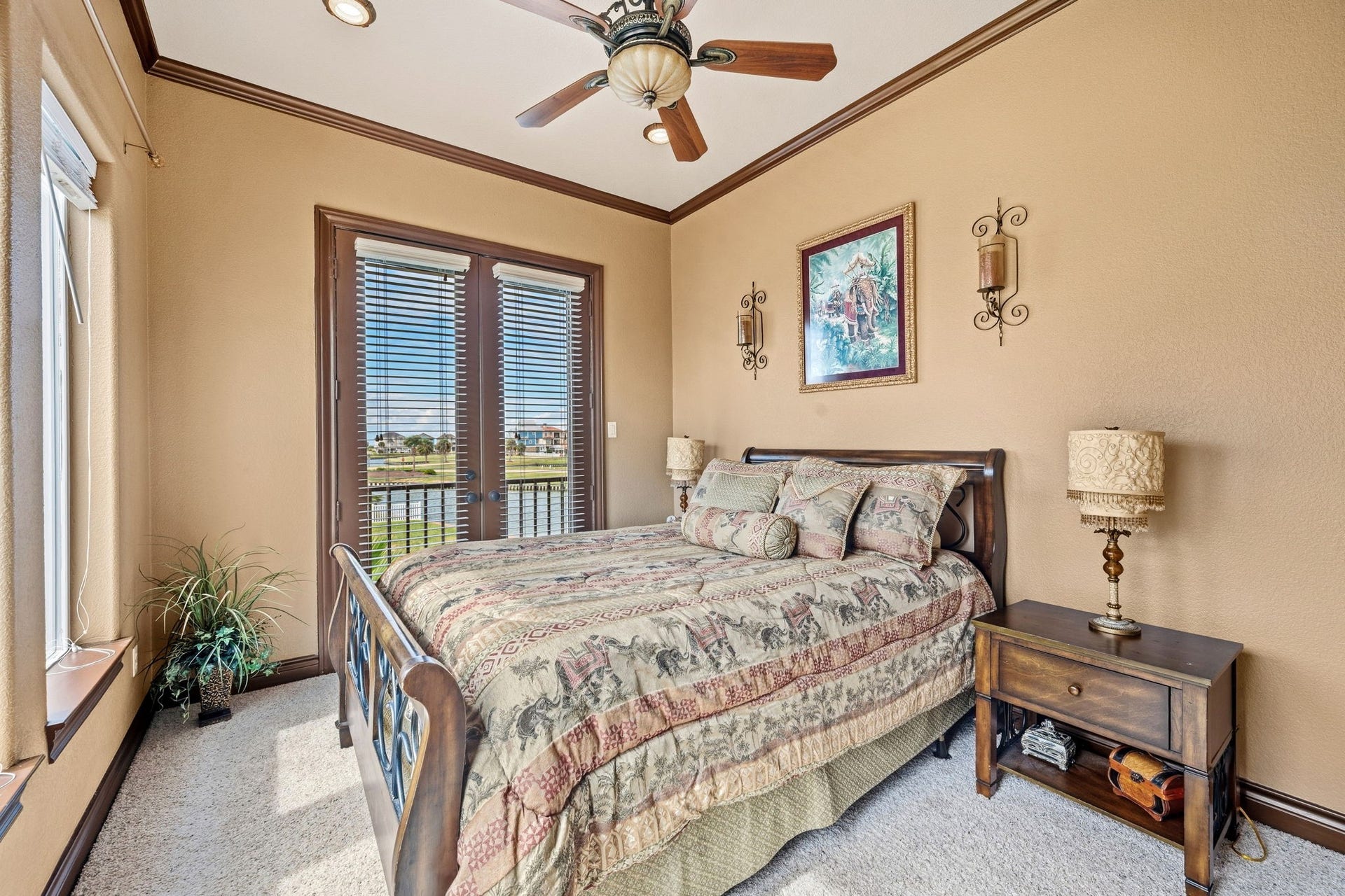26 Half Moon, Hitchcock, TX 77563 1st floor bedroom featuring warm earth tones, a stylish ceiling fan, and abundant natural light through French doors with scenic views.