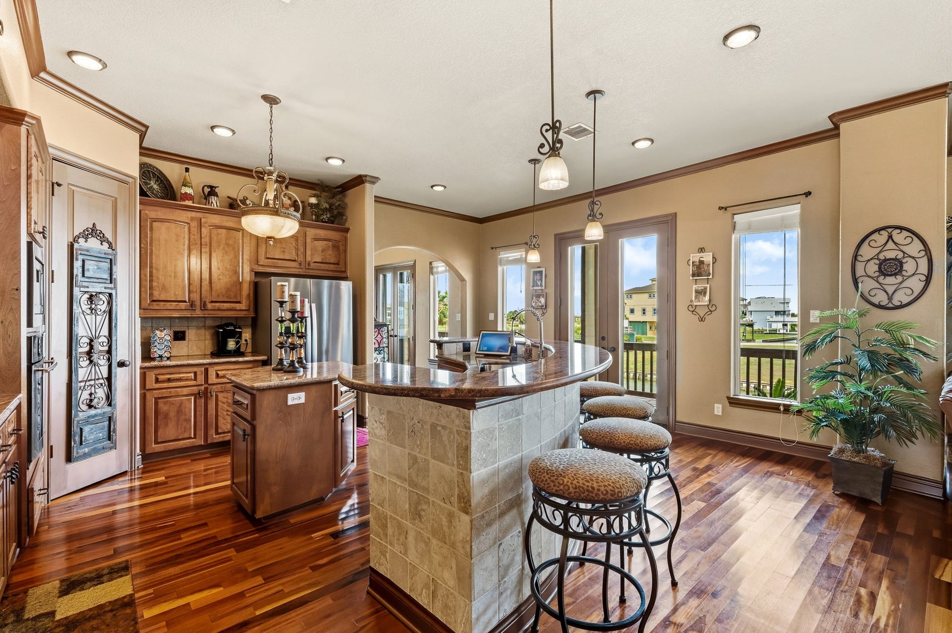 26 Half Moon, Hitchcock, TX 77563 Elegant kitchen with rich wood cabinetry, stainless steel appliances, and a stylish breakfast bar. The open layout and ample natural light create a warm and inviting atmosphere, perfect for entertaining.