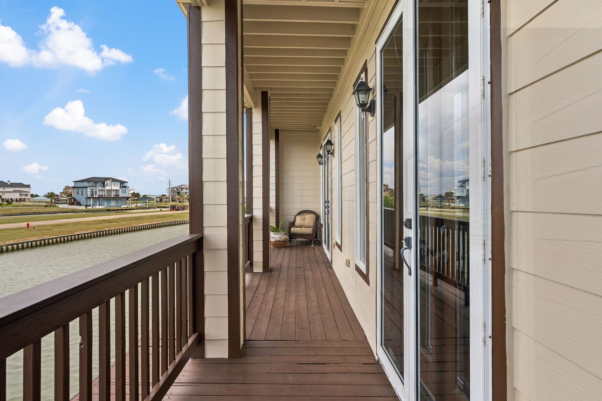 26 Half Moon, Hitchcock, TX 77563 Charming waterfront balcony with elegant wood flooring and glass doors, offering serene canal views and a peaceful retreat.