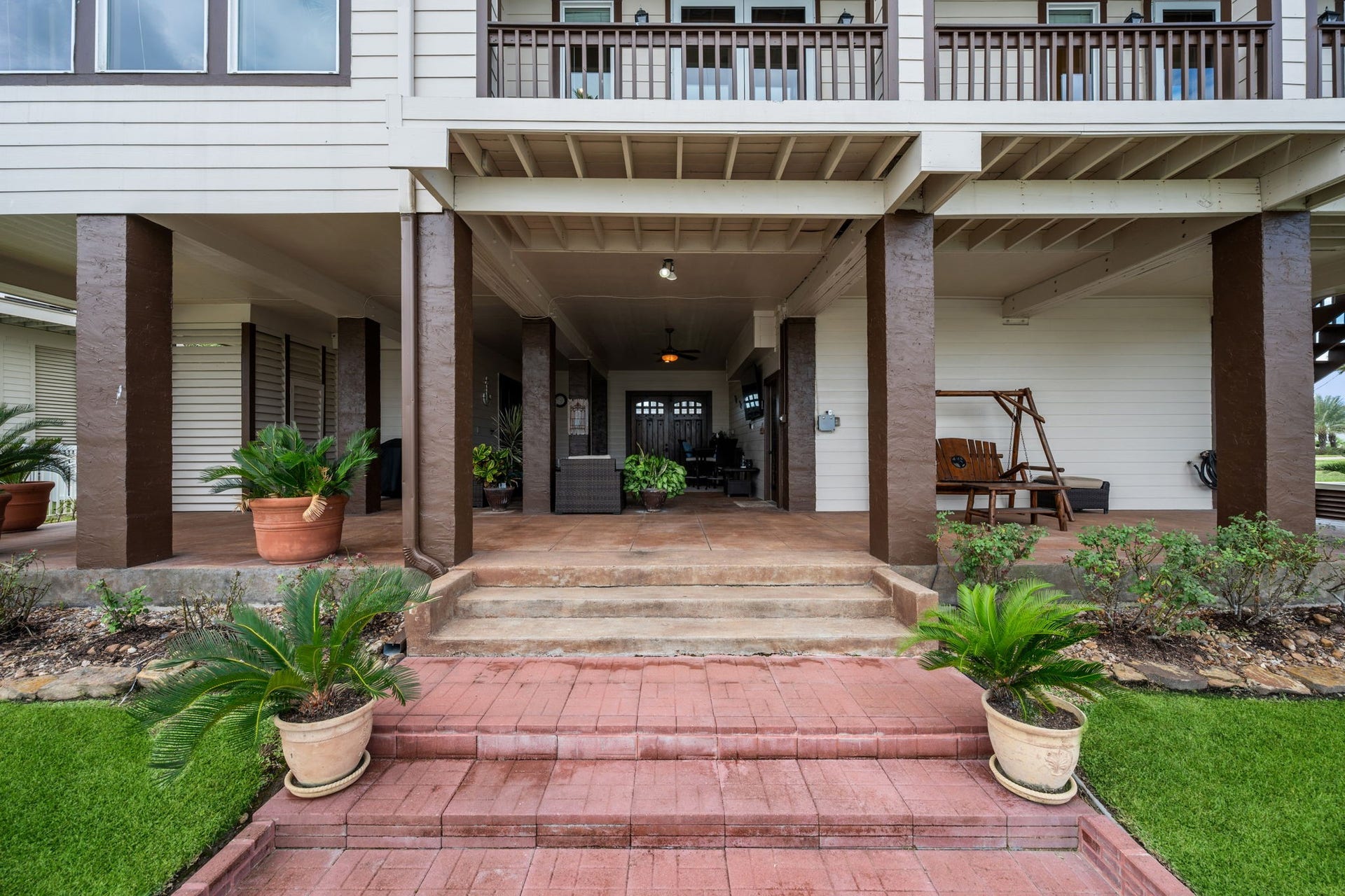 26 Half Moon, Hitchcock, TX 77563 Charming covered patio featuring elegant columns, cozy seating area, and lush potted greenery, perfect for relaxation and entertaining.