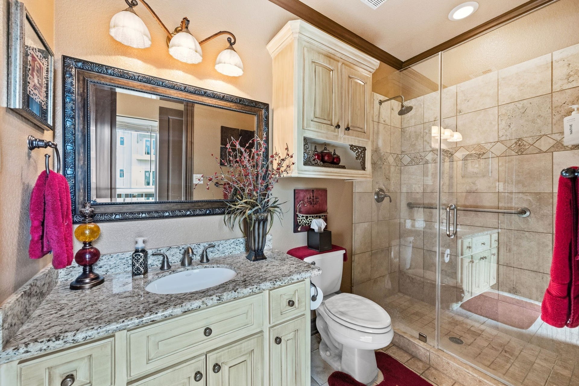 26 Half Moon, Hitchcock, TX 77563 Elegant ensuite bathroom featuring a granite countertop, large framed mirror, and a spacious glass-enclosed shower with stylish tilework.
