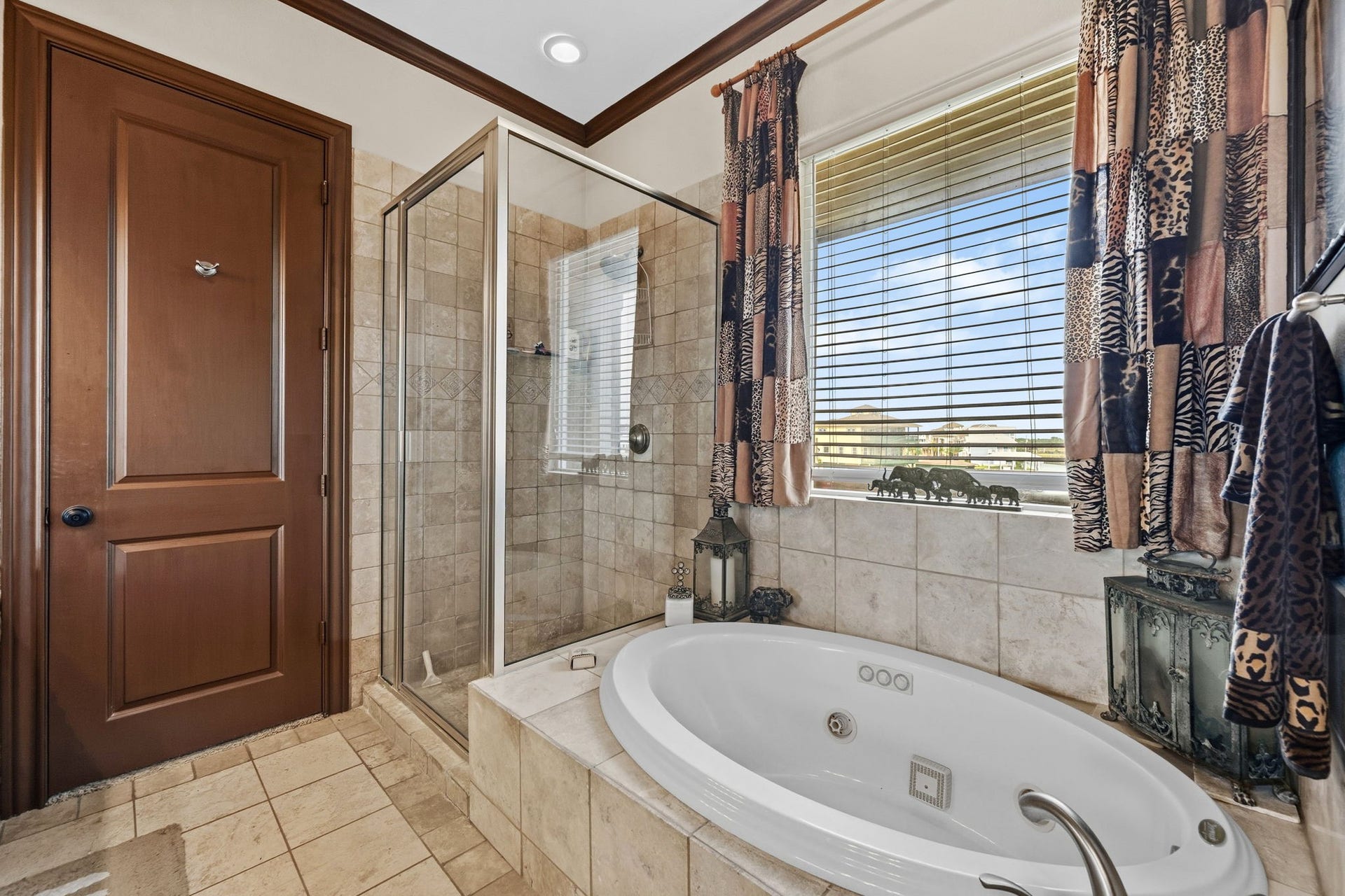 26 Half Moon, Hitchcock, TX 77563 Luxurious bathroom featuring a spacious tiled shower and a relaxing jacuzzi tub, accented by elegant curtains and warm wood finishes.