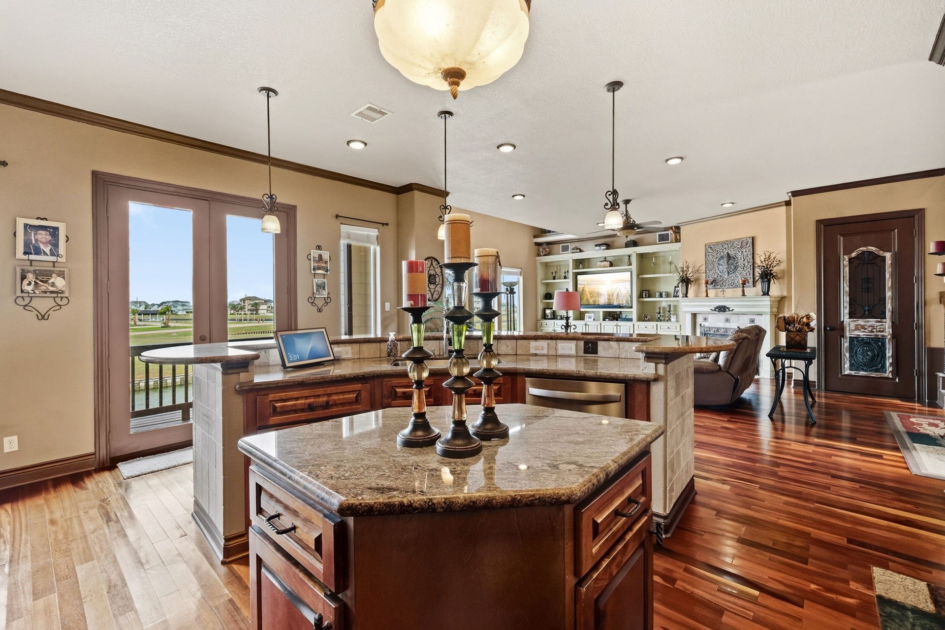 26 Half Moon, Hitchcock, TX 77563 Spacious open-concept living area featuring elegant hardwood floors, a large kitchen island with granite countertops, and ample natural light from expansive windows overlooking a serene view.