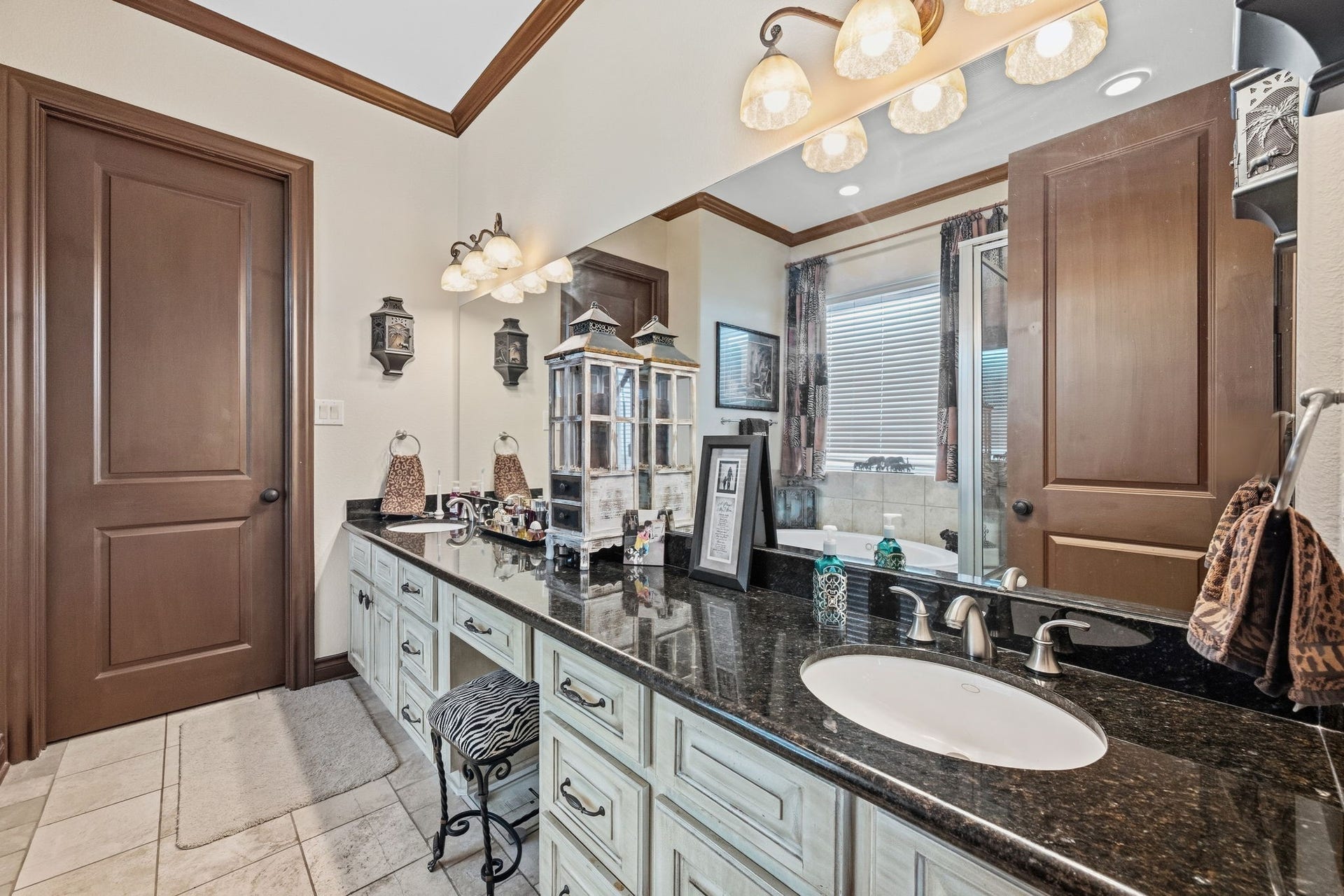 26 Half Moon, Hitchcock, TX 77563 Elegant bathroom featuring a double sink vanity with sleek granite countertops, stylish lighting, and ample storage, complemented by a cozy bathtub for relaxation.